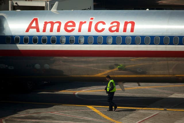 An airport worker walks past an American Airlines Inc. plane standing at a gate at LaGuardia Airport in the Queens borough of New York, U.S., on Monday, April 25, 2011. American Airlines Inc. is trying to grab market share in New York, the biggest and possibly most-contested U.S. aviation market, with terminal upgrades at LaGuardia Airport. Delta Air Lines Inc.'s bid to redo its space remains in limbo, bogged down in talks with federal regulators and US Airways Group Inc. about access to more landing rights. Photographer: Michael Nagle/Bloomberg