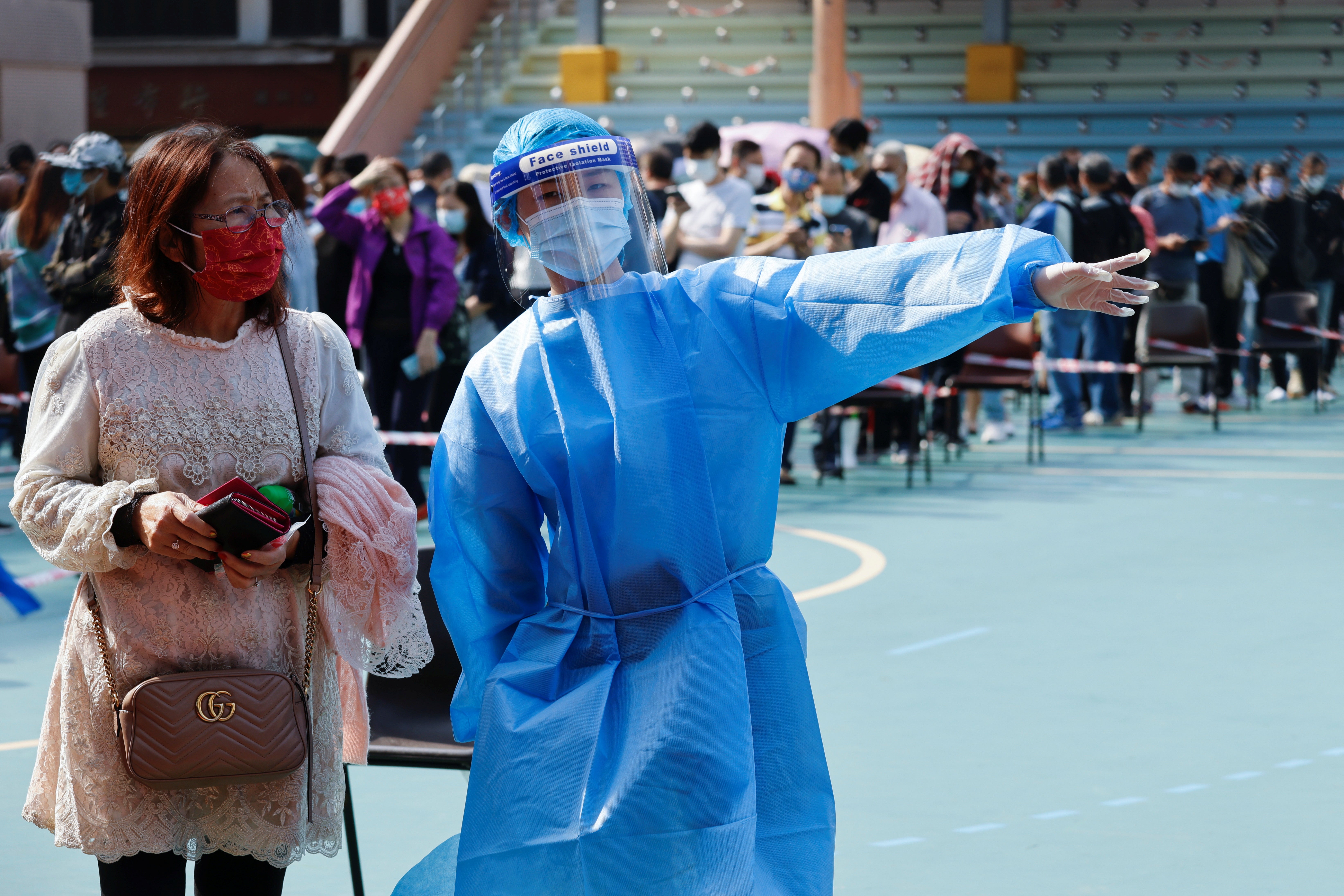 A health worker guides a woman to queue up at a makeshift community testing centre for the coronavirus disease (COVID-19), in Hong Kong, China