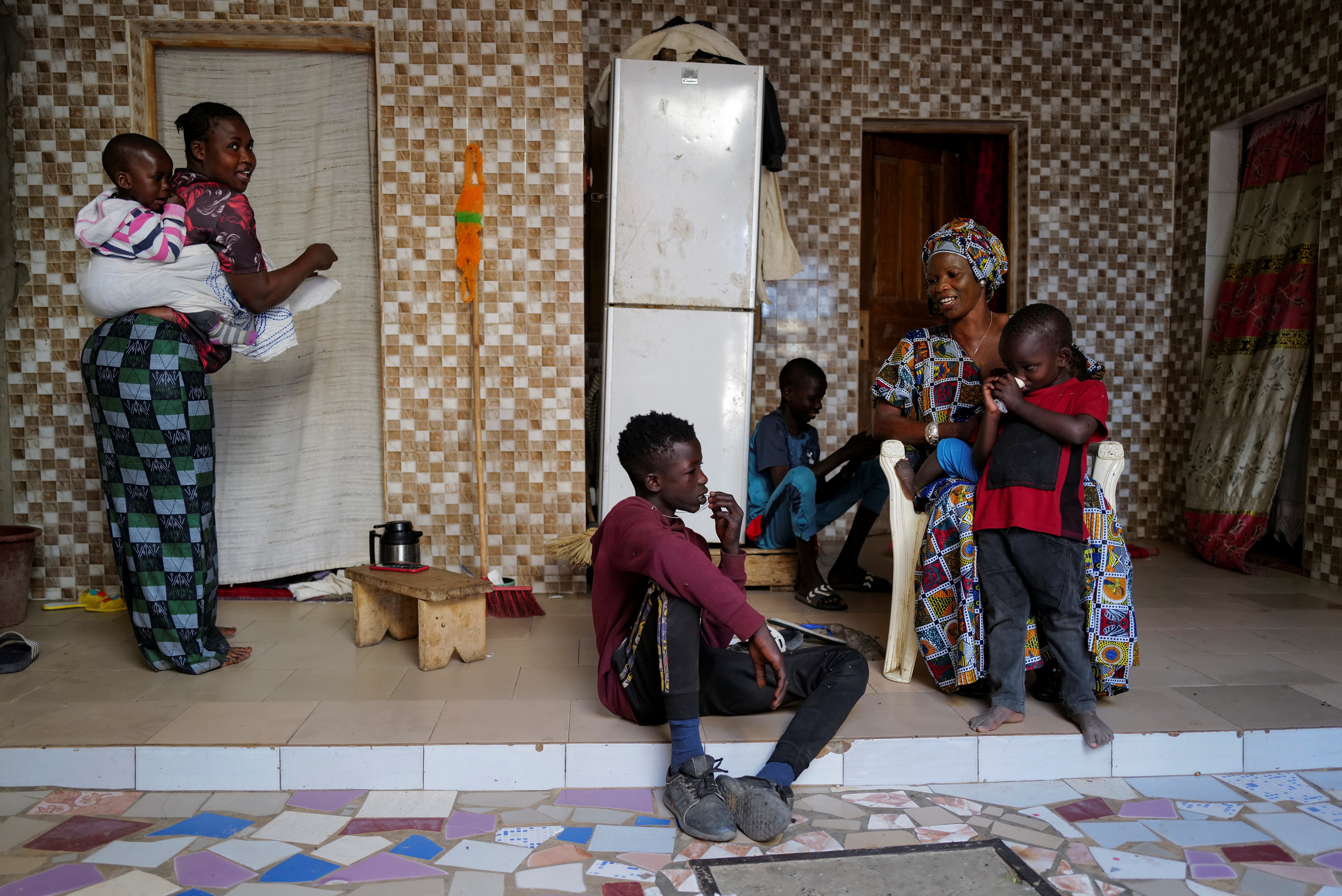 Diop sits next to his mother Ndeye Boye and brothers as his sister, carrying her son, watches on at their home in Niaga