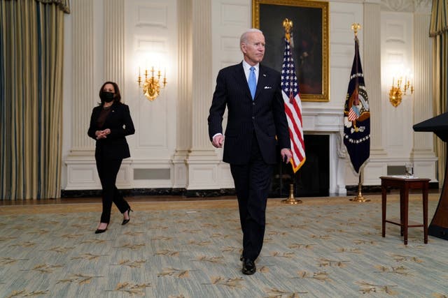 President Joe Biden holds a face mask after speaking about efforts to combat COVID-19, in the State Dining Room of the White House, Tuesday, March 2, 2021, in Washington. Vice President Kamala Harris is at left