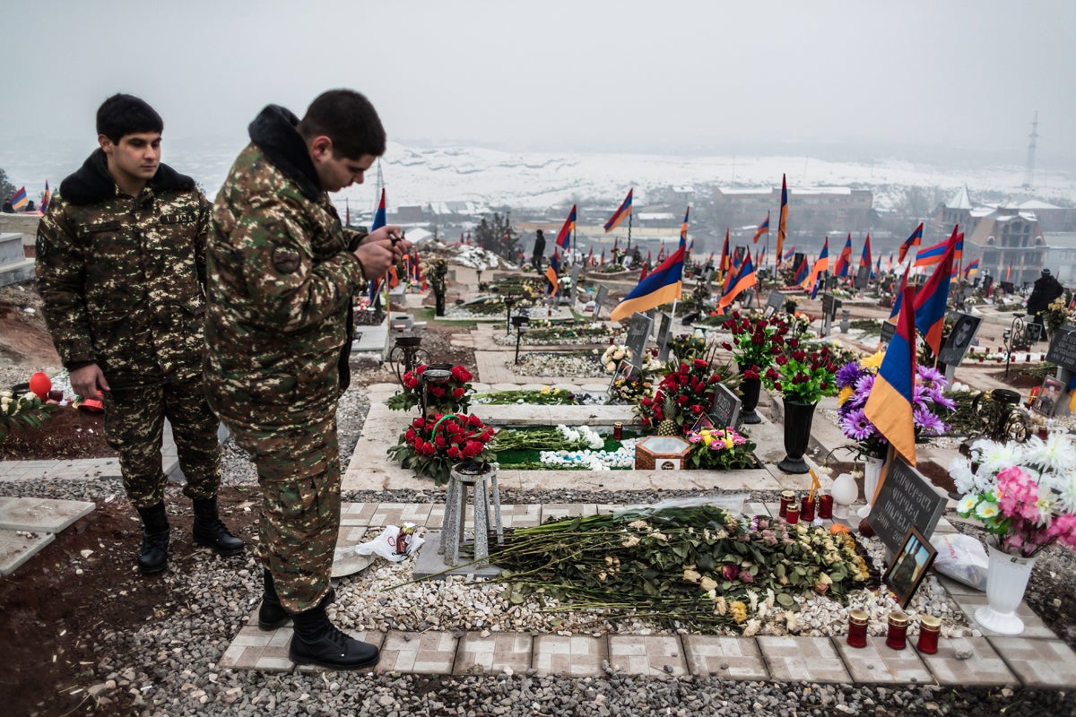 Armenian soldiers Erik and Vahan pay tribute to a comrade before his grave at the Military Heroes’ Cemetery in Yerevan, Armenia