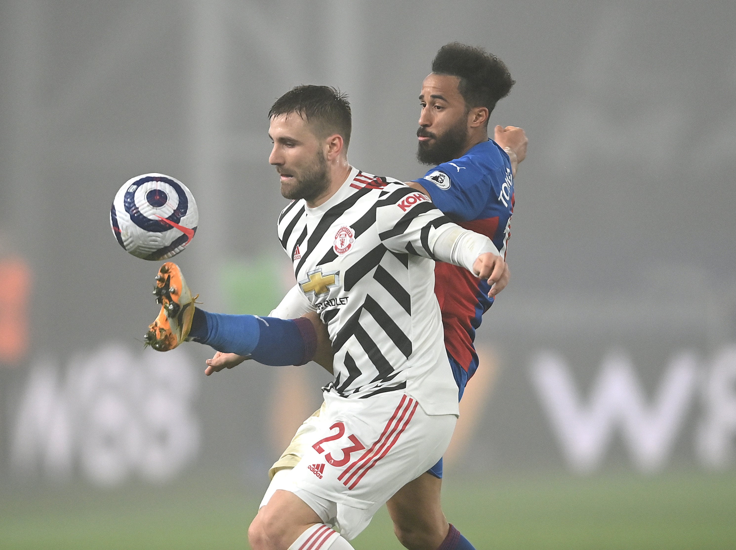 Manchester United defender Luke Shaw jostles with Andros Townsend
