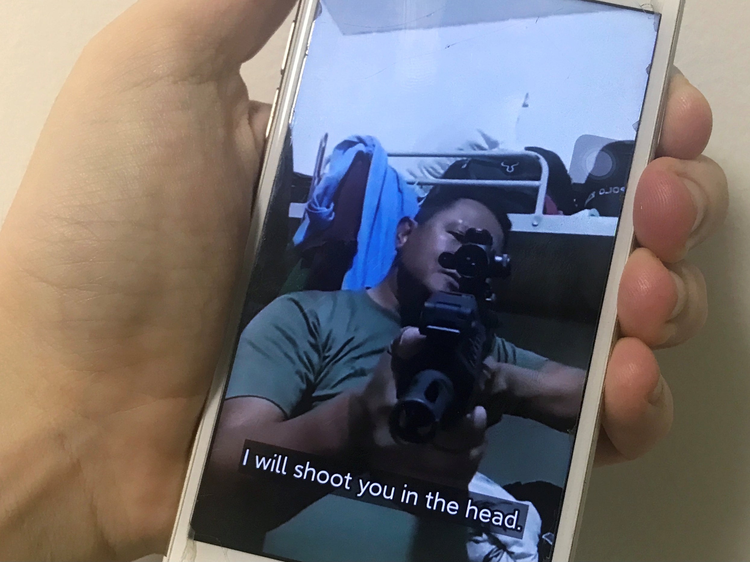A mobile phone shows a picture of a Myanmar man in an army shirt threatening to shoot anti-coup protesters