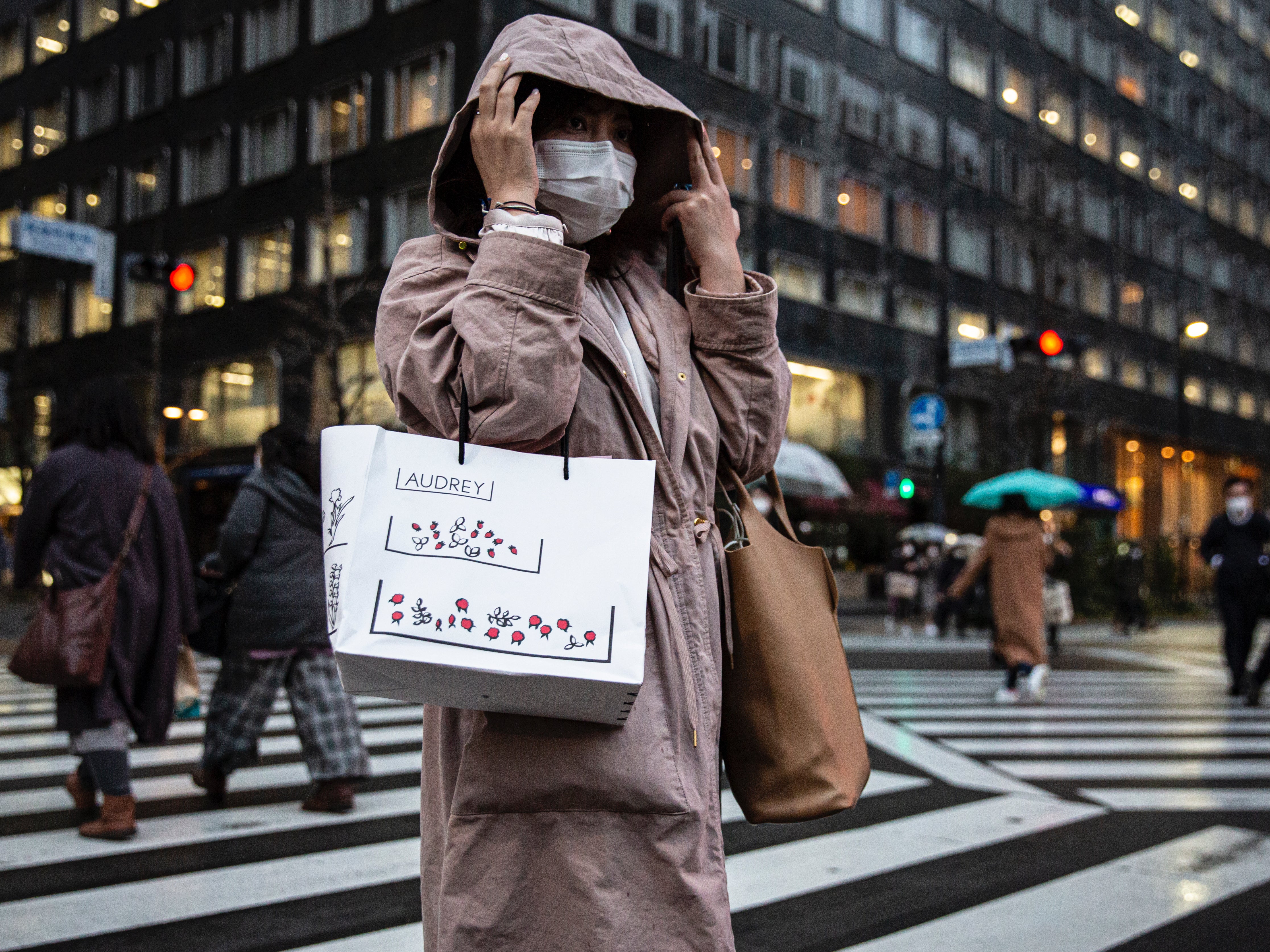 File: A woman wearing a face mask crosses a road on in Tokyo