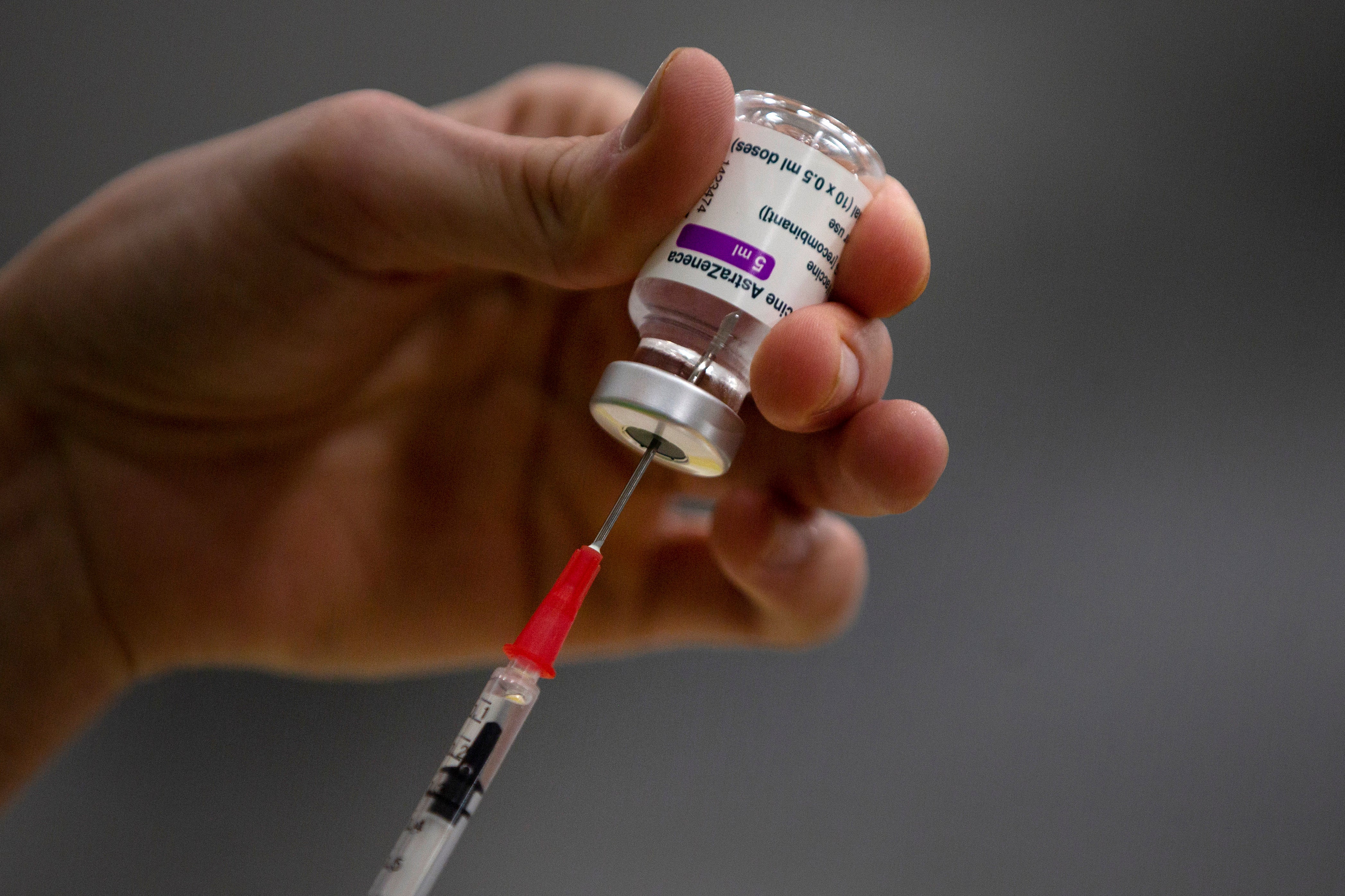 A pharmacist prepares a syringe from a vial of the AstraZeneca coronavirus vaccine