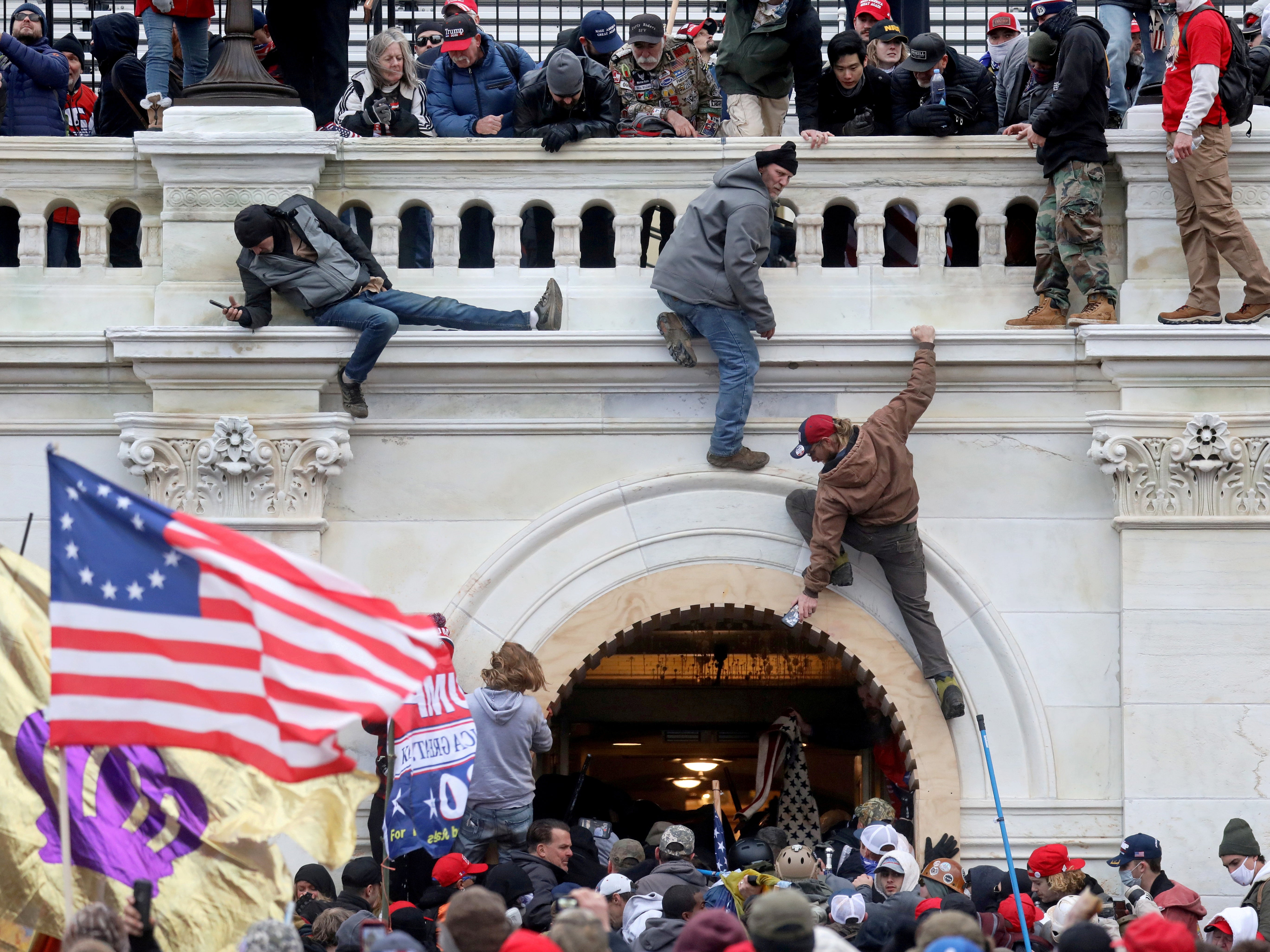 A mob of supporters of former U.S. President Donald Trump fight with members of law enforcement at a door they broke open as they storm the US Capitol Building in Washington, DC, on 6 January 2021