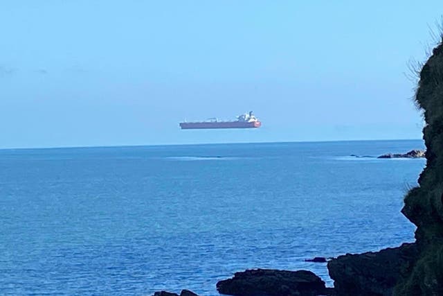 A tanker appears to float above the sea when viewed from the Cornwall coast