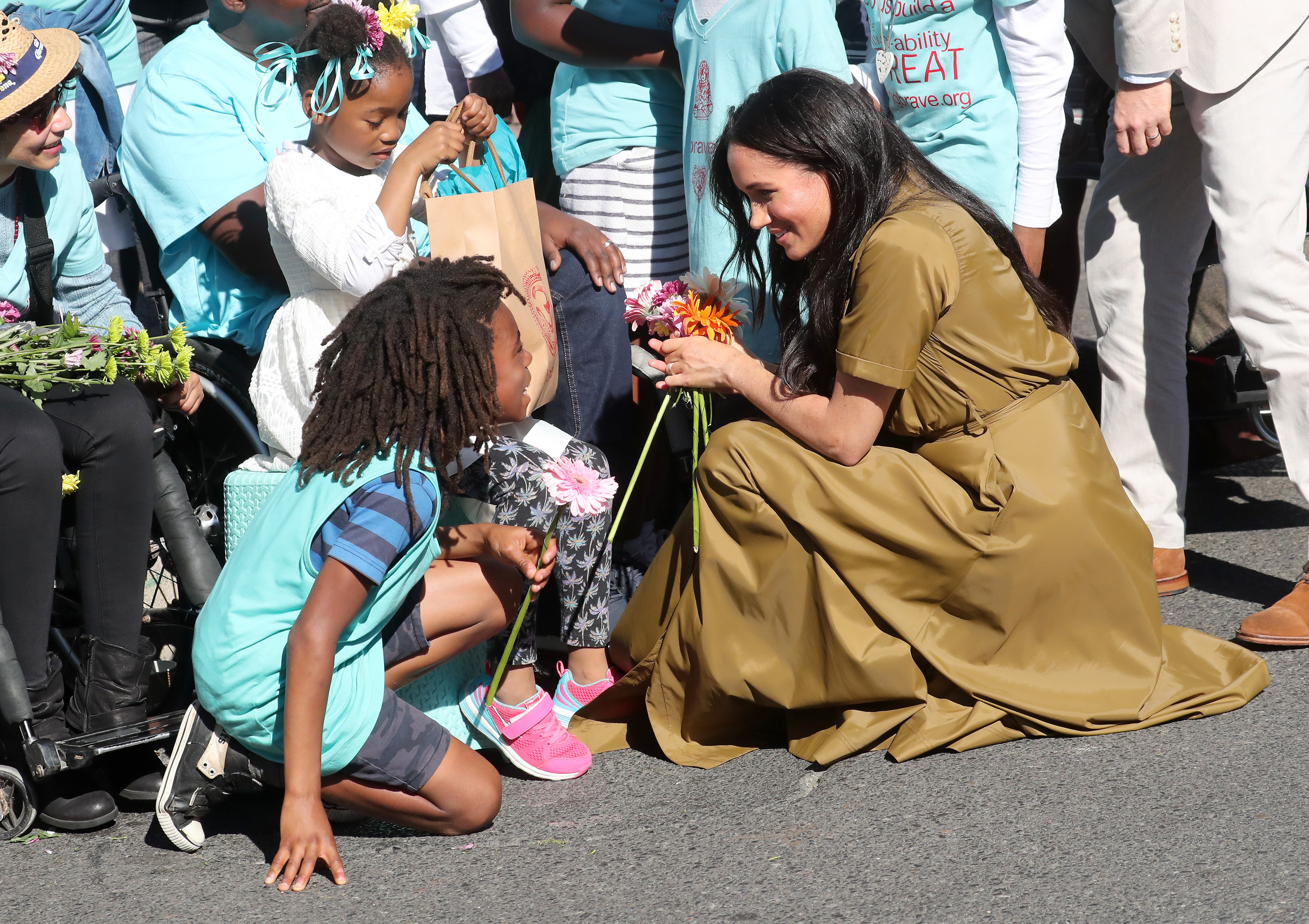 CAPE TOWN, SOUTH AFRICA - SEPTEMBER 24: Meghan, Duchess of Sussex meets a young wellwisher as she and Prince Harry, Duke of Sussex walk through the colourful and multicultural neighbourhood of Bo-Kaap on Heritage Day during their royal tour of South Africa on September 24, 2019 in Cape Town, South Africa.