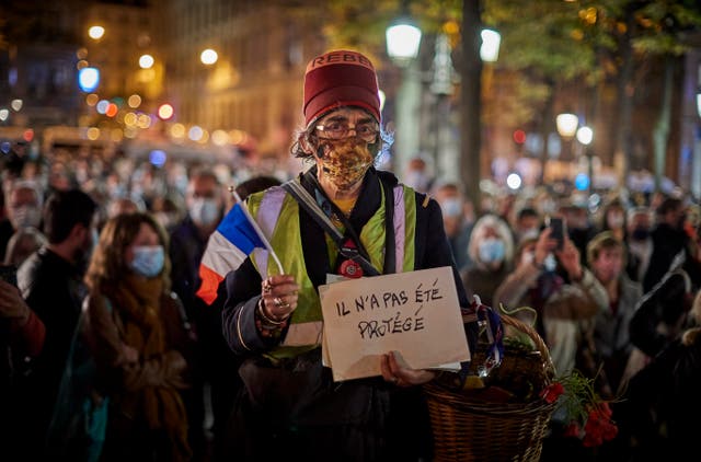 Archivo: Un miembro de la multitud que observa el Tributo Nacional al maestro de escuela asesinado Samuel Paty sostiene un tricolor francés y un letrero que dice 'No estaba protegido' en la Place de la Sorbonne el 21 de octubre de 2020 en París, Francia.