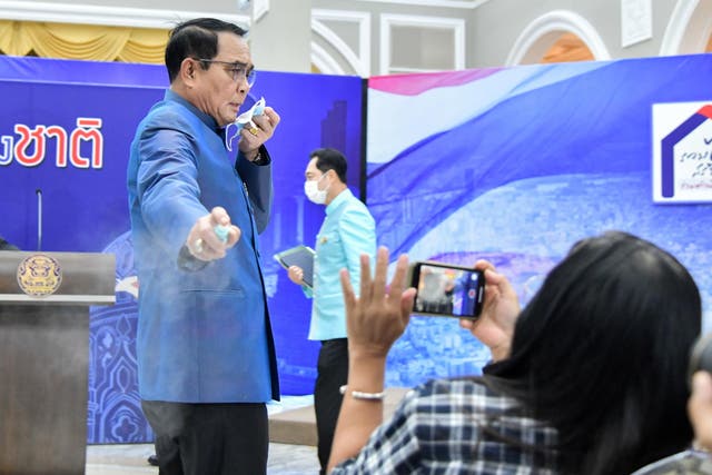<p>Thai prime minister Prayuth Chan-ocha sprays hand sanitiser at journalists </p>
