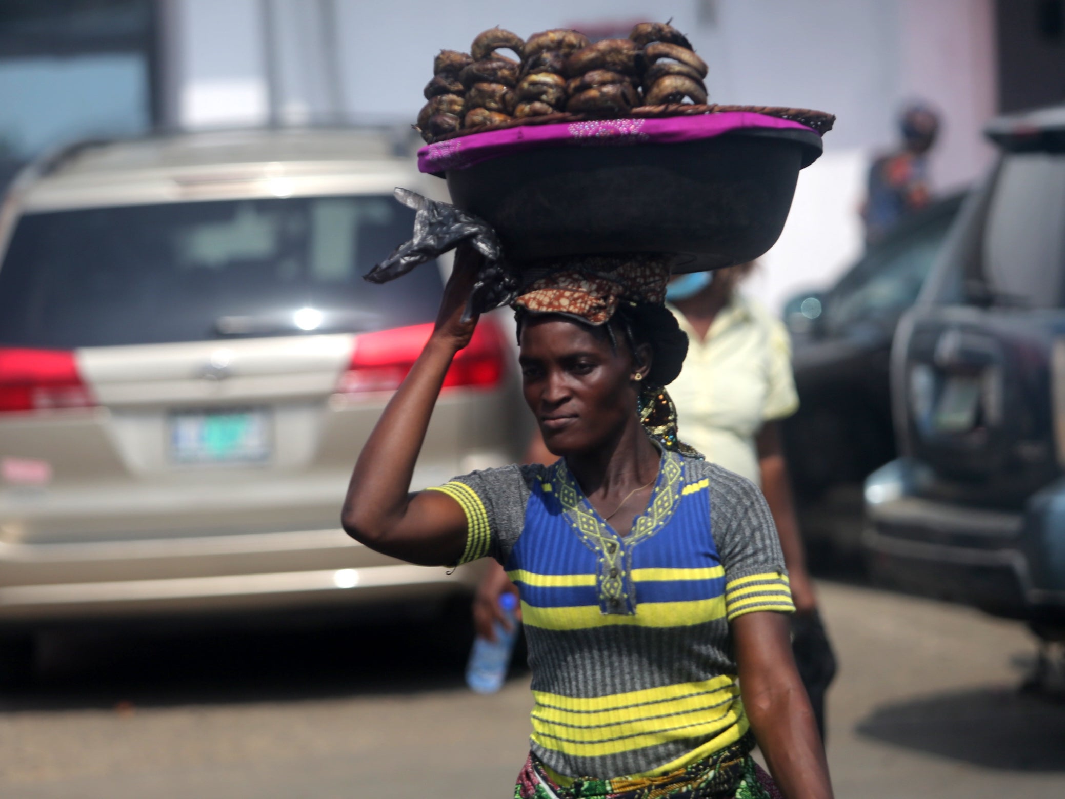 A woman hawks smoked fish displayed on a plastic bowl along a road in Oyingbo district of Lagos, Nigeria