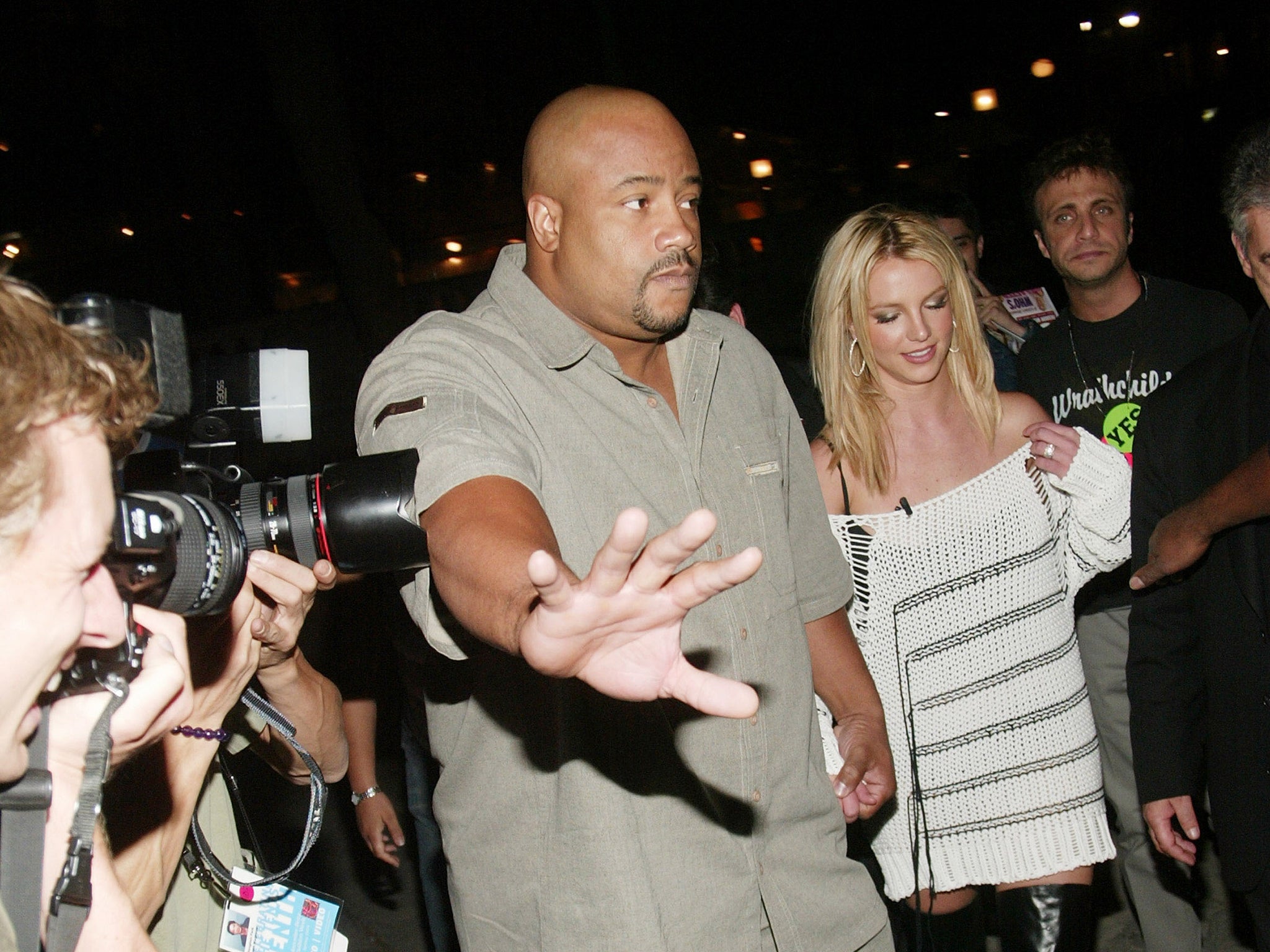 A bodyguard for Britney Spears holds back paparazzi photographers in 2003