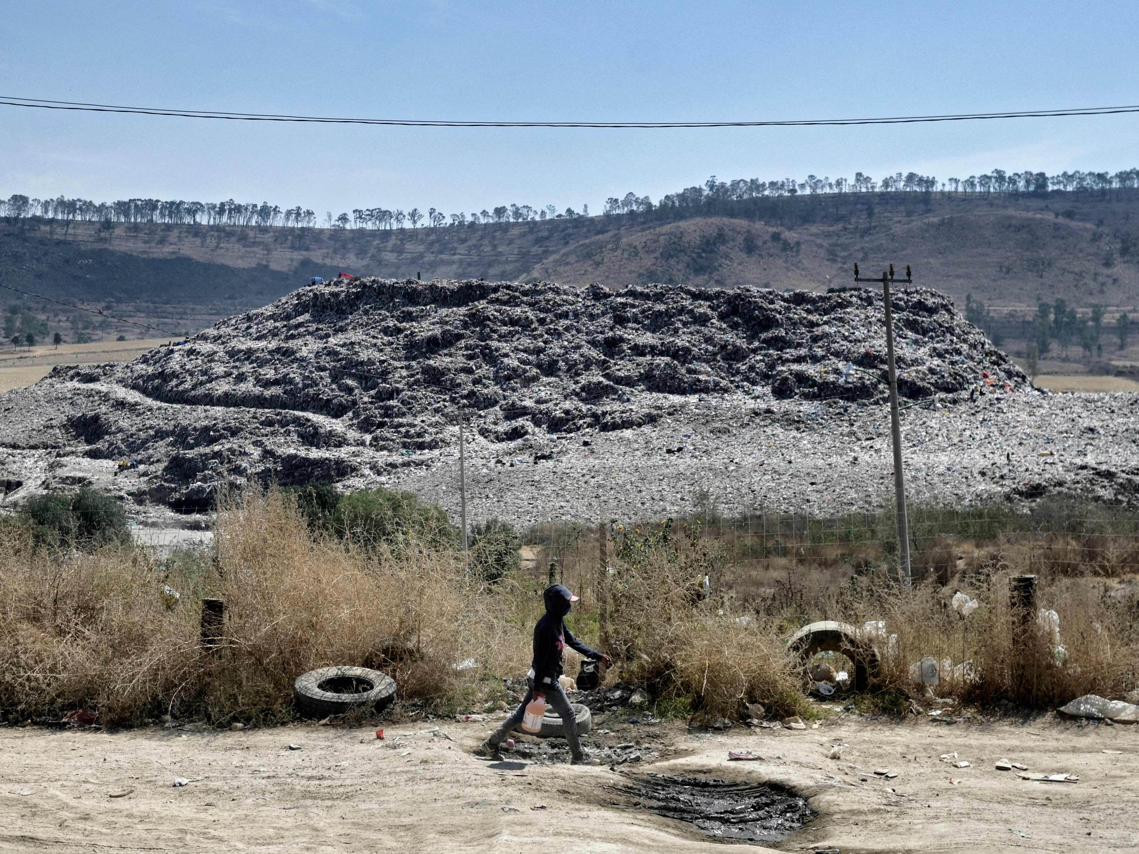 A child walks at the Escalerillas neighborhood with the municipal garbage dump in the background in Chimalhuacan, Mexico state
