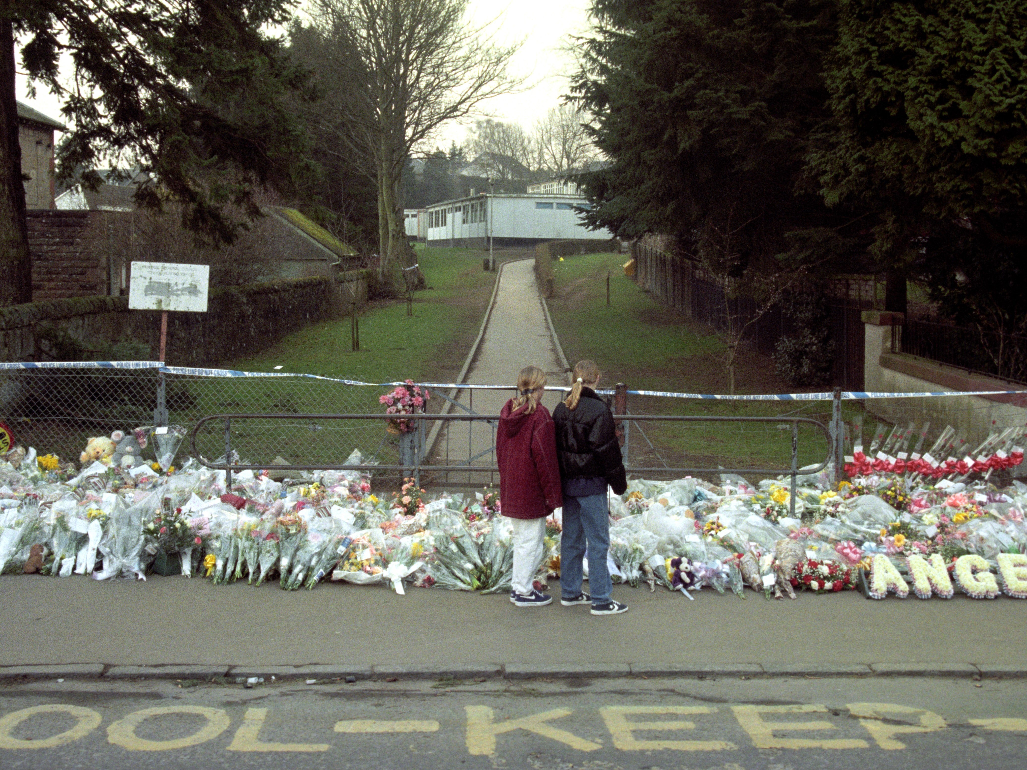 Two children stand in front of the flower tribute to those who died at Dunblane Primary School