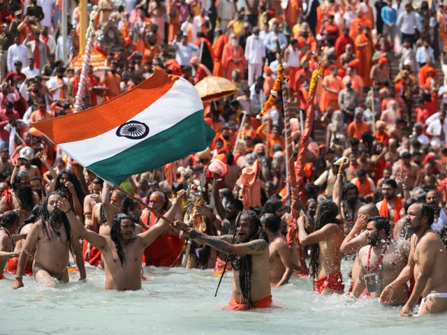 A Naga Sadhu, or a Hindu holy man, waves the Indian flag as he takes a dip in the Ganges river