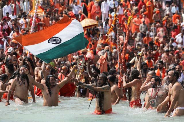 A Naga Sadhu, or a Hindu holy man, waves the Indian flag as he takes a dip in the Ganges river