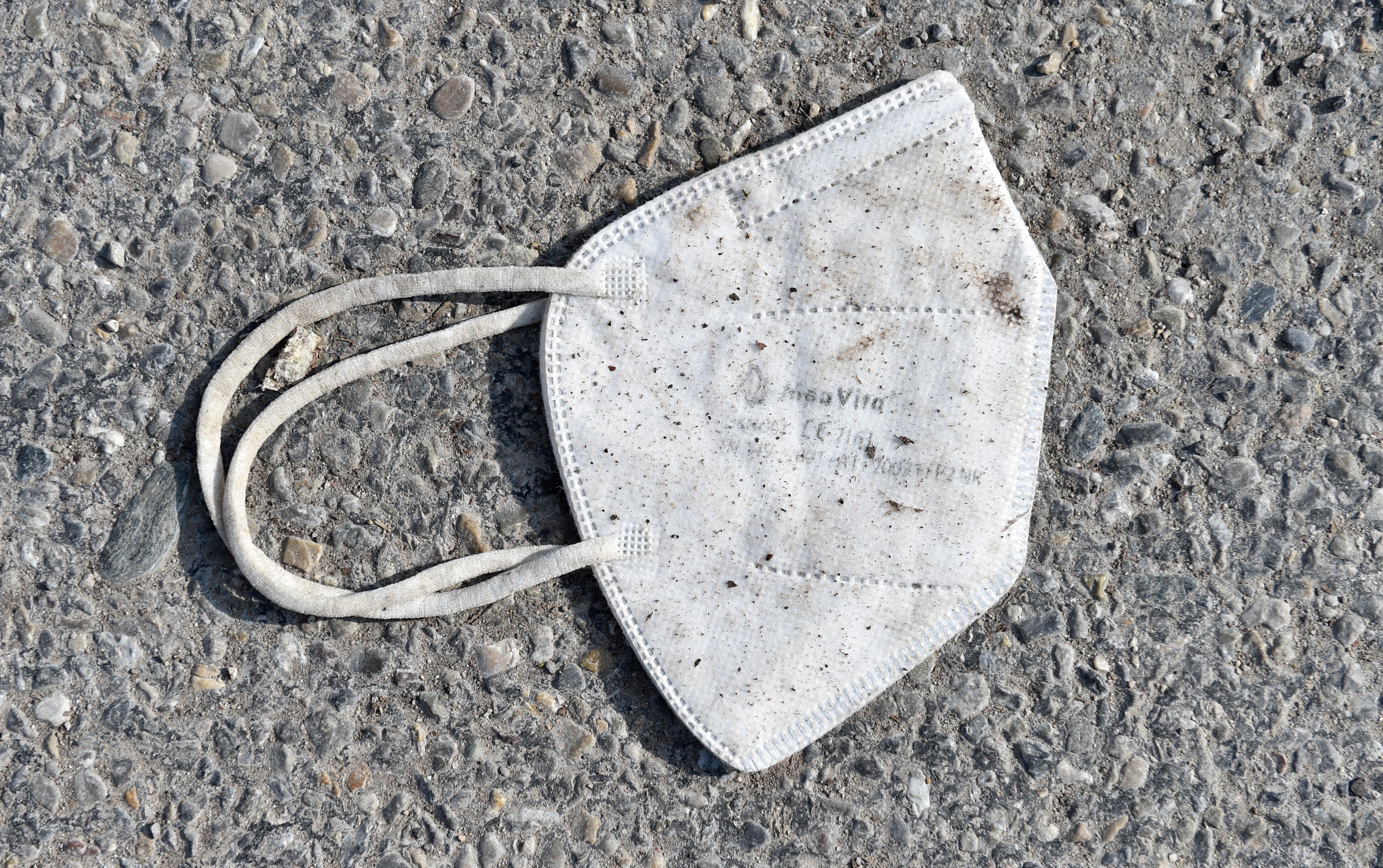 A discarded FFP2 protective face mask lies on a street.
