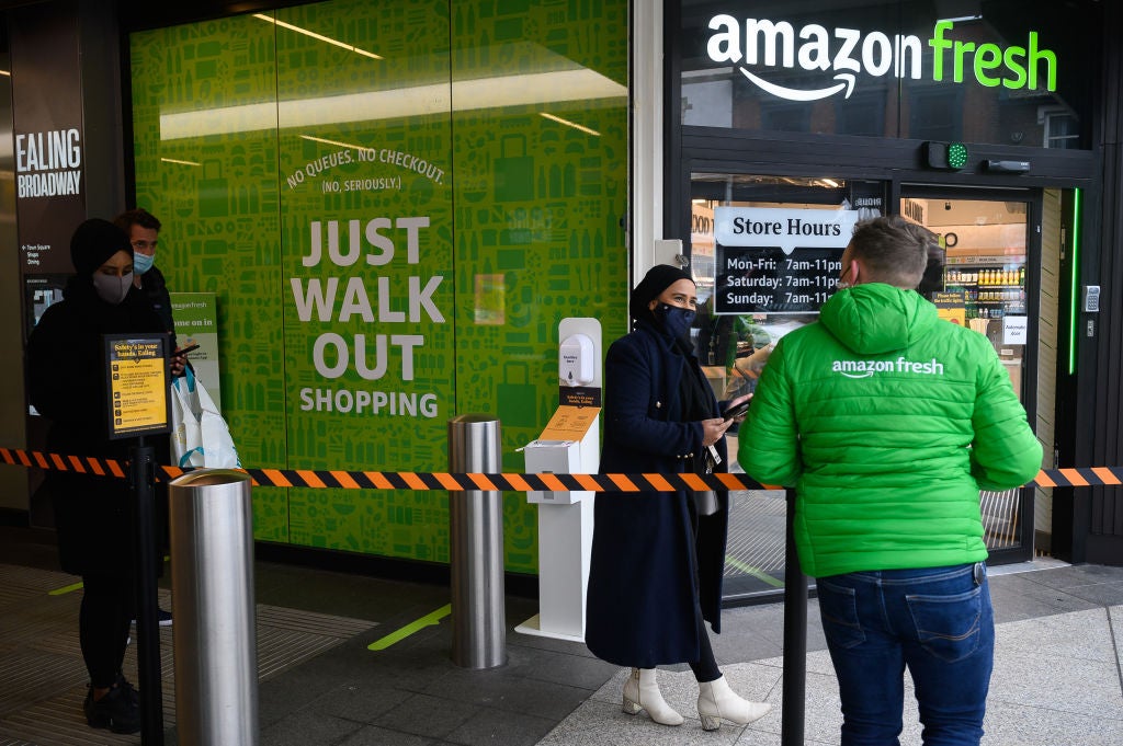 Members of staff assist customers as they wait to enter the UK’s first branch of Amazon Fresh in Ealing, west London