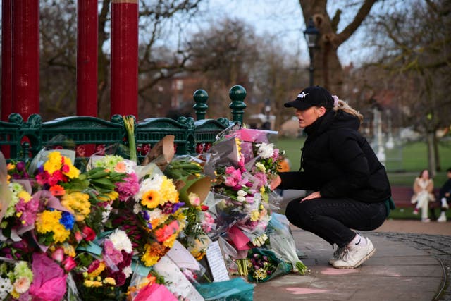 <p>A woman leaves flowers at the bandstand on Clapham Common, on Friday</p>