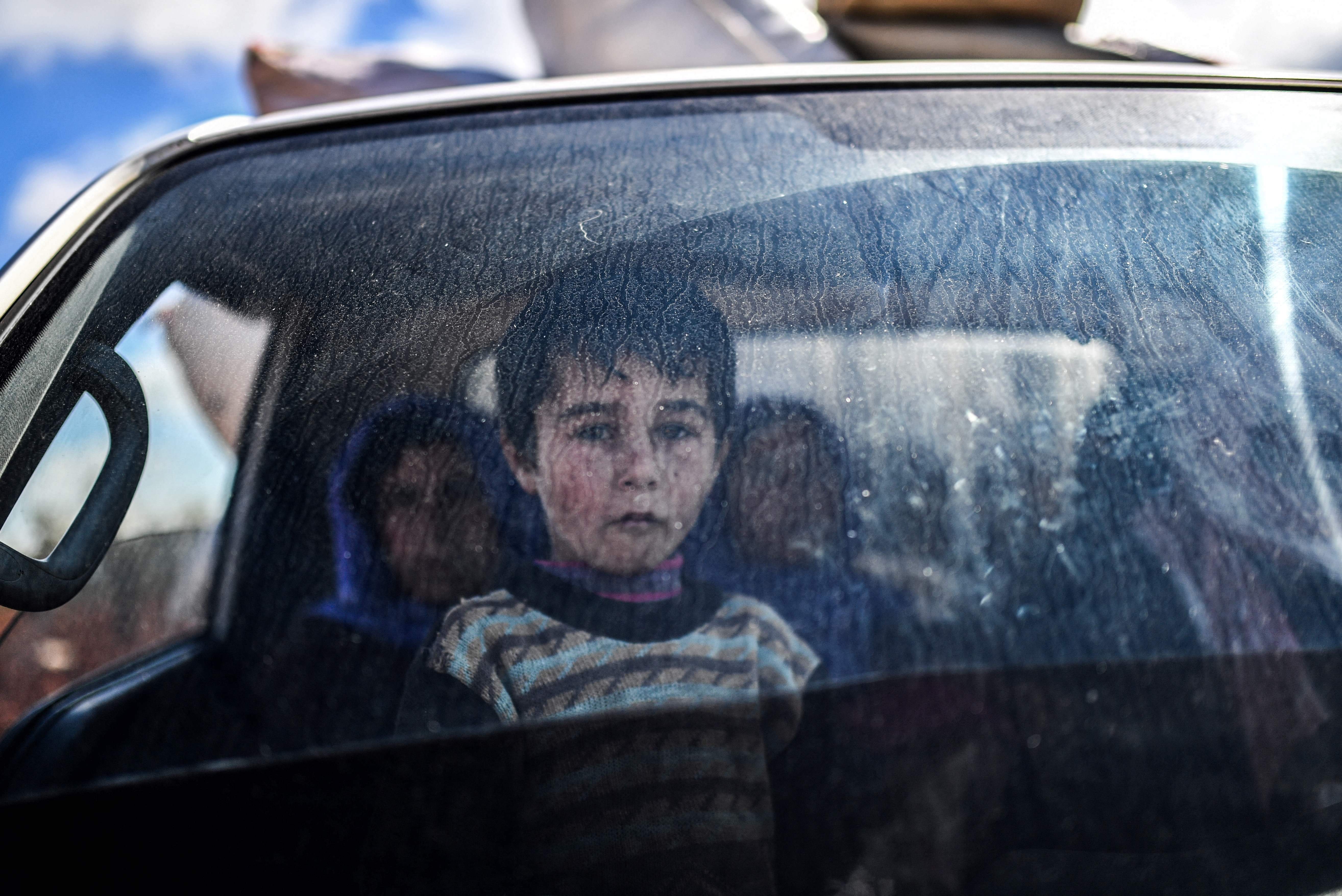 A Syrian child looks on as people arrive at a checkpoint in the village of Anab, northern Syria,