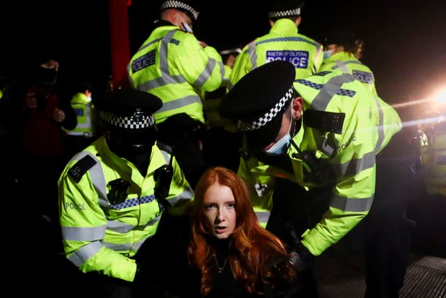<p>Police detain a woman as people mourn Sarah Everard at Clapham Common vigil</p>