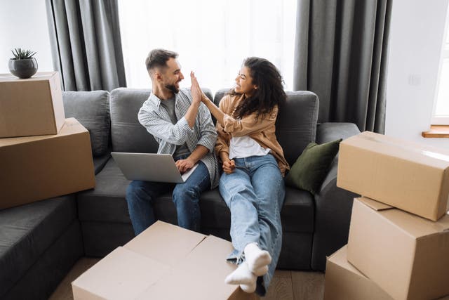 Man and woman high-fiving, surrounded by boxes after moving house