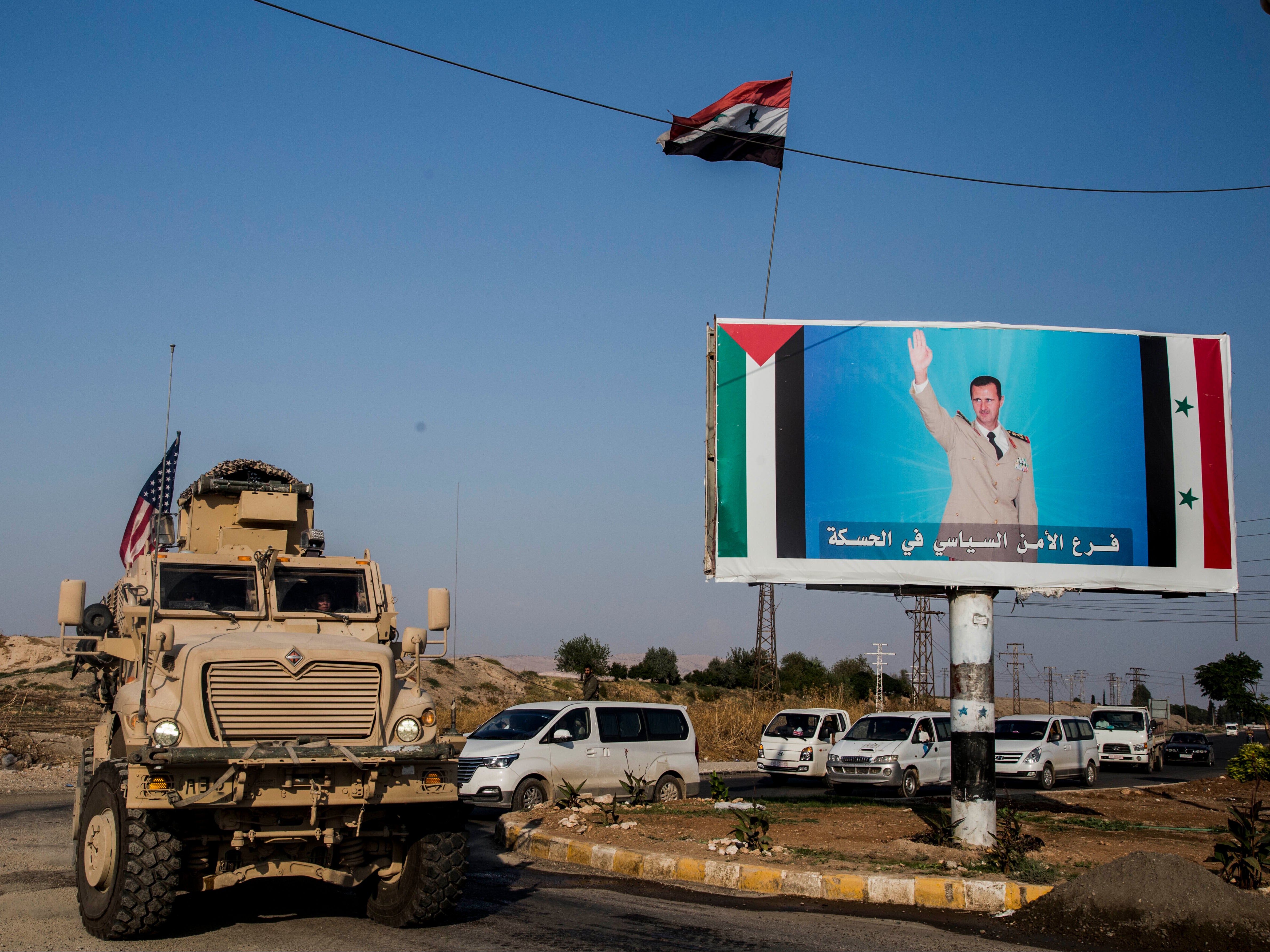 US military convoy in north-eastern Syria in 2019, next to Assad poster