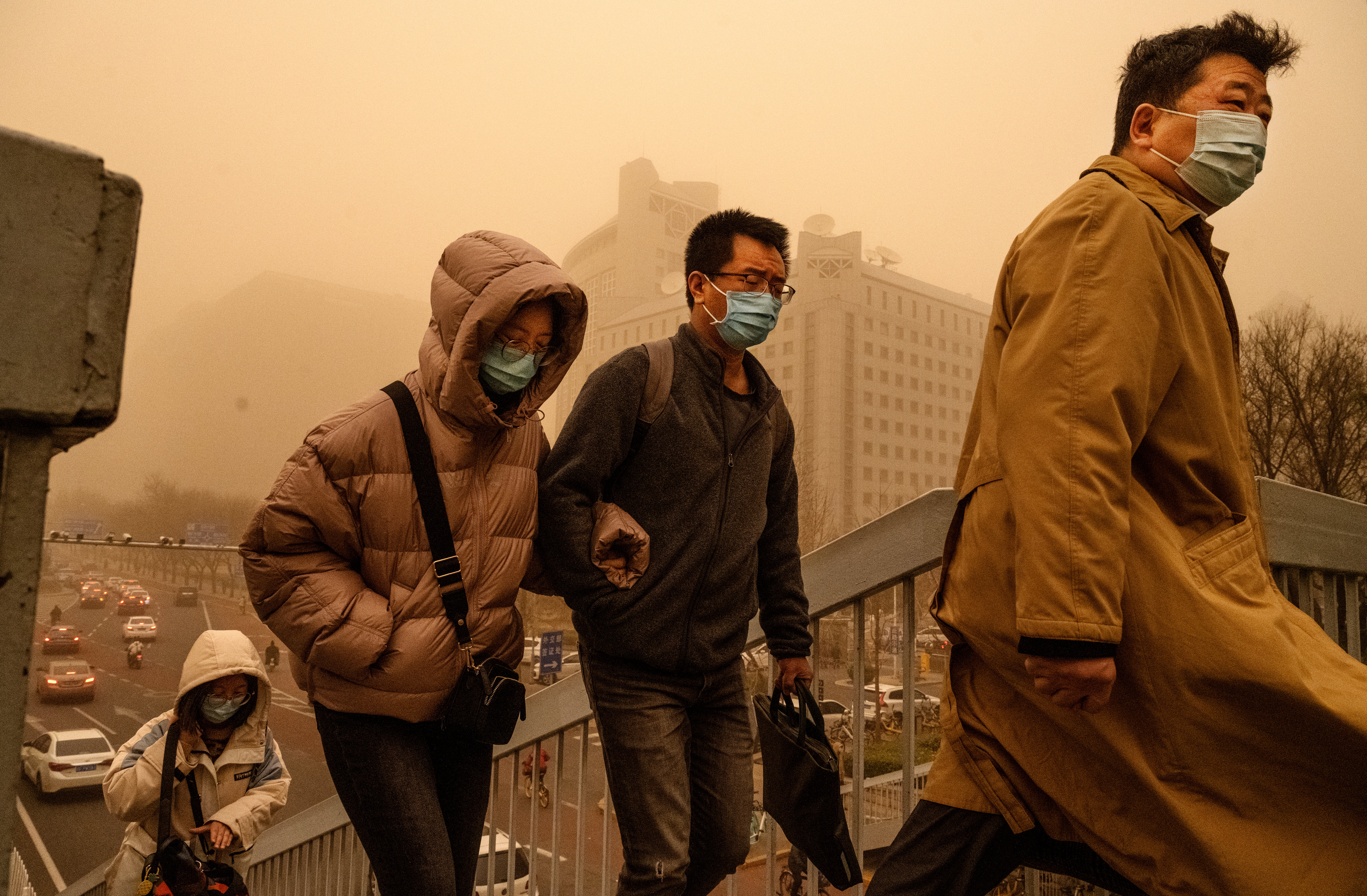 People wear protective masks as they commute during a sandstorm in Beijing