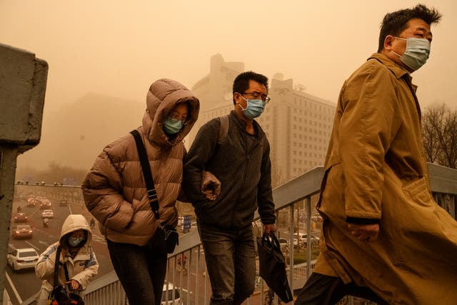 <p>People wear protective masks as they commute during a sandstorm in Beijing</p>