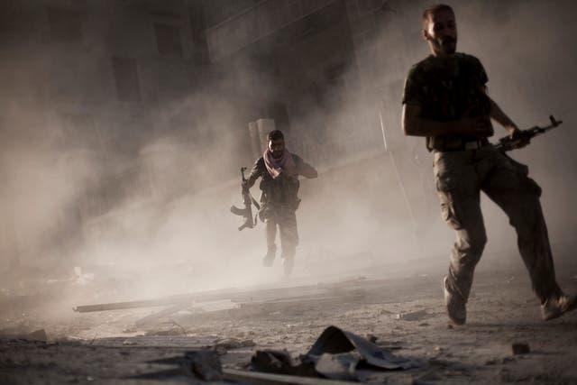 Free Syrian Army fighters run away after attacking a Syrian Army tank during fighting in the Izaa district in Aleppo, Syria