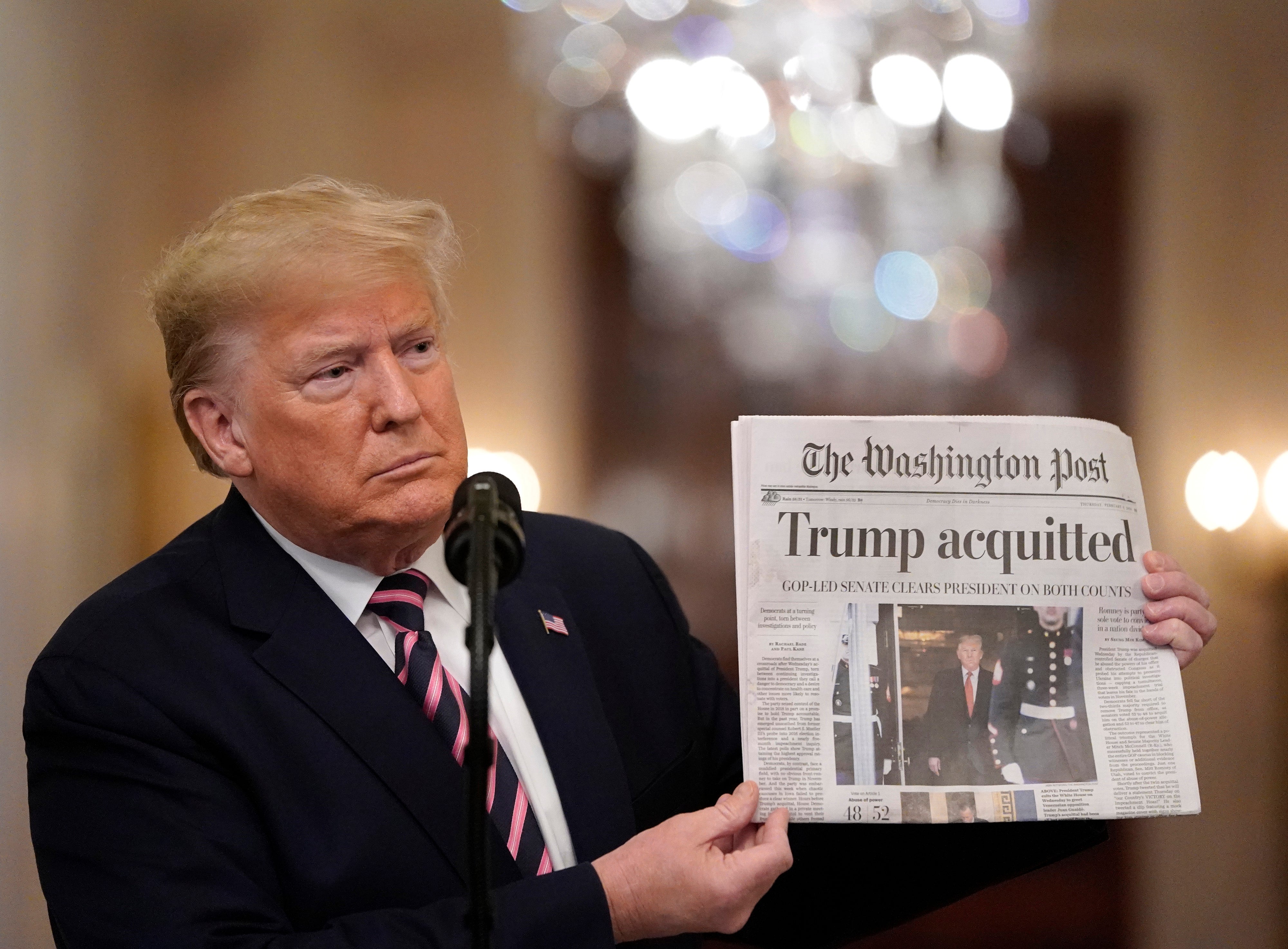 US President Donald Trump holds a copy of The Washington Post as he speaks in the East Room of the White House one day after the US Senate acquitted on two articles of impeachment, ion February 6, 2020 in Washington, DC