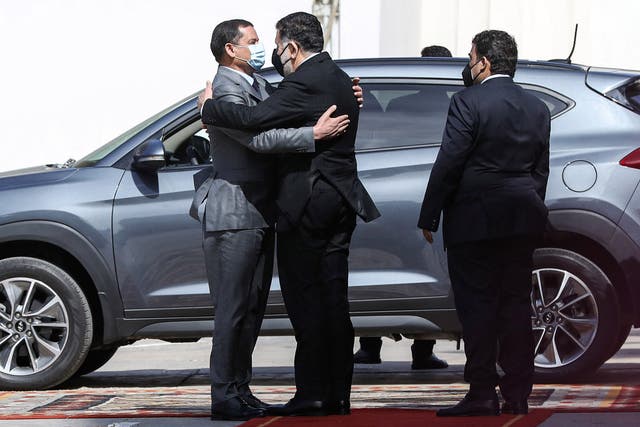 <p>Mohamed al-Manfi, head of Libya's presidency council, looks on as interim prime minister Abdul Hamid Dbeibah embraces outgoing GNA head Fayez Serraj during the formal handover in Tripoli </p>