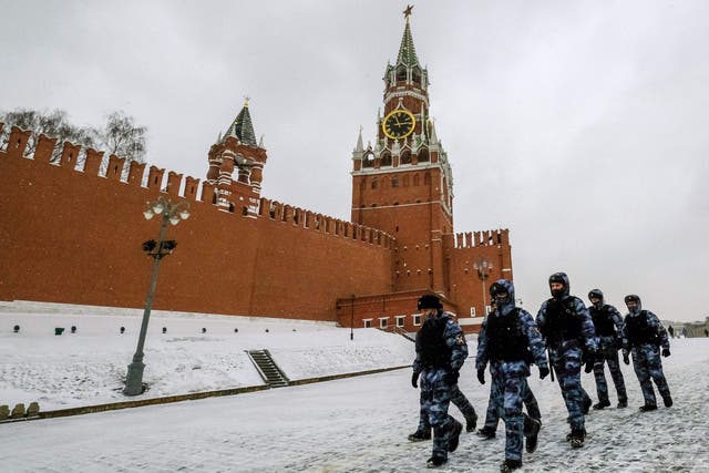 Police officers wearing protective face masks walk past the Spasskaya Tower of the Kremlin in Moscow on March 13, 2021