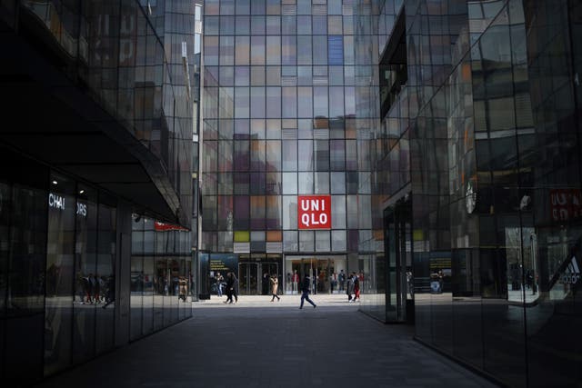 <p>People walk past a Uniqlo store in Beijing on February 28, 2019</p>
