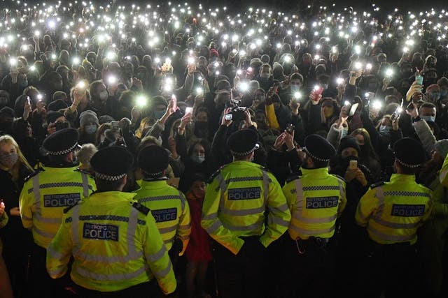<p>Police officers form a cordon as people turn on their phone lights at a vigil for Sarah Everard</p>