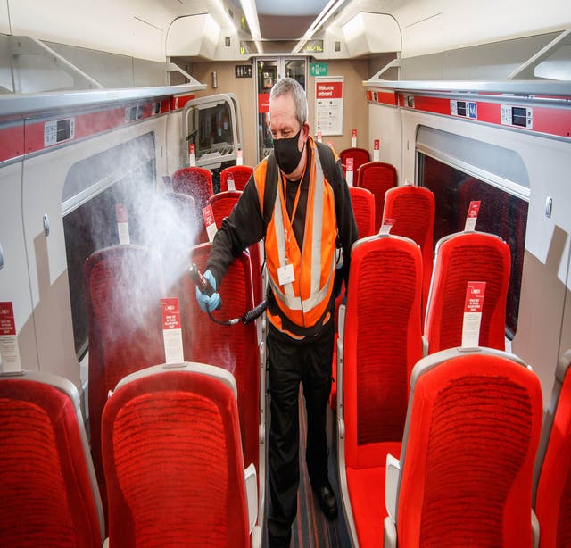 A cleaner uses a fogging machine to clean a train carriage early in the morning