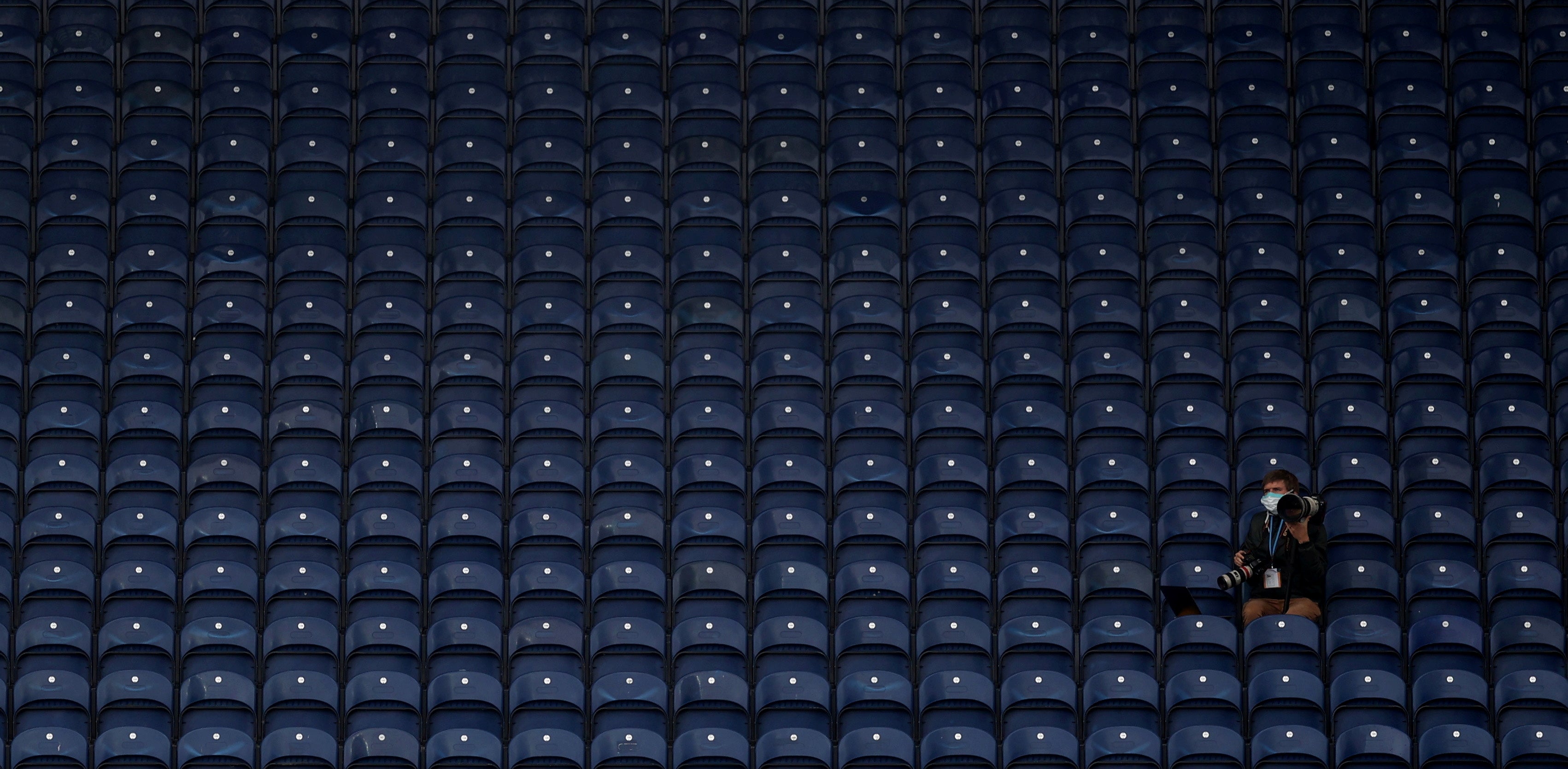 A photographer sits in an empty stand during a Championship match in July