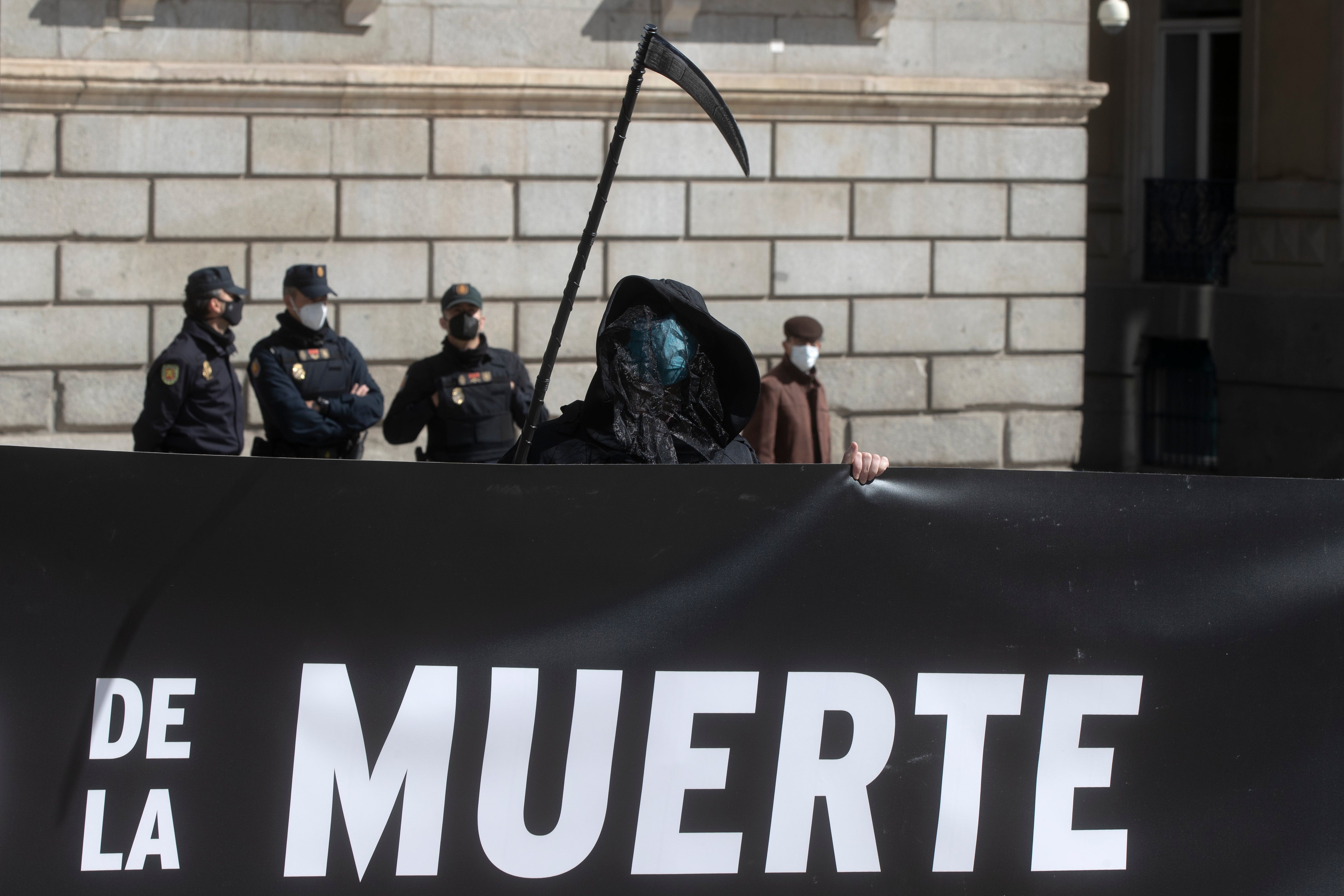 An anti Euthanasia protester stands in front of police officers outside the Spanish Parliament