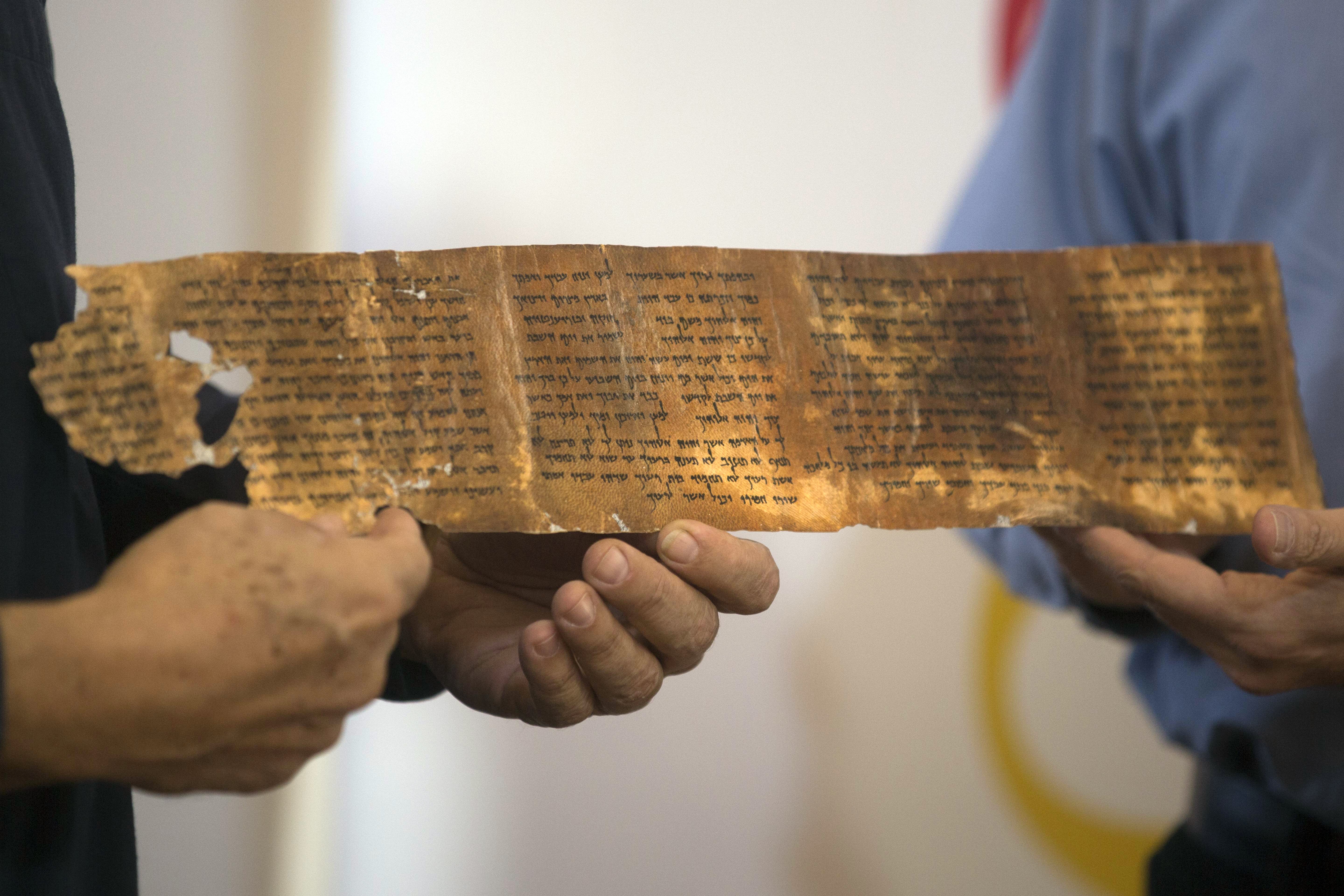 Keep scrolling: Researchers hold a replica of one of the seven ancient biblical manuscripts found in a cave at Qumran near the Dead Sea