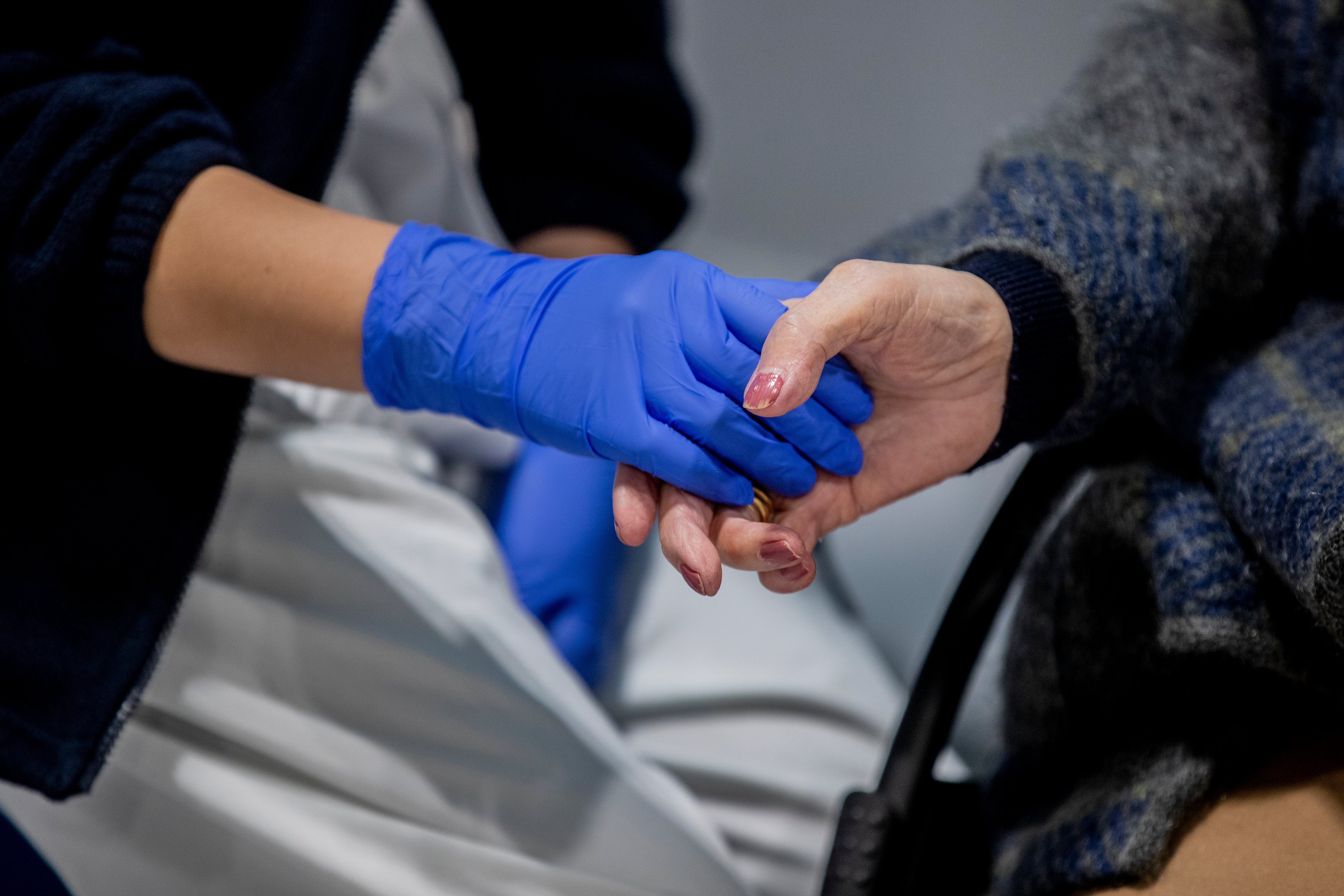 A health worker holds the hand of a woman before being vaccinated in Madrid