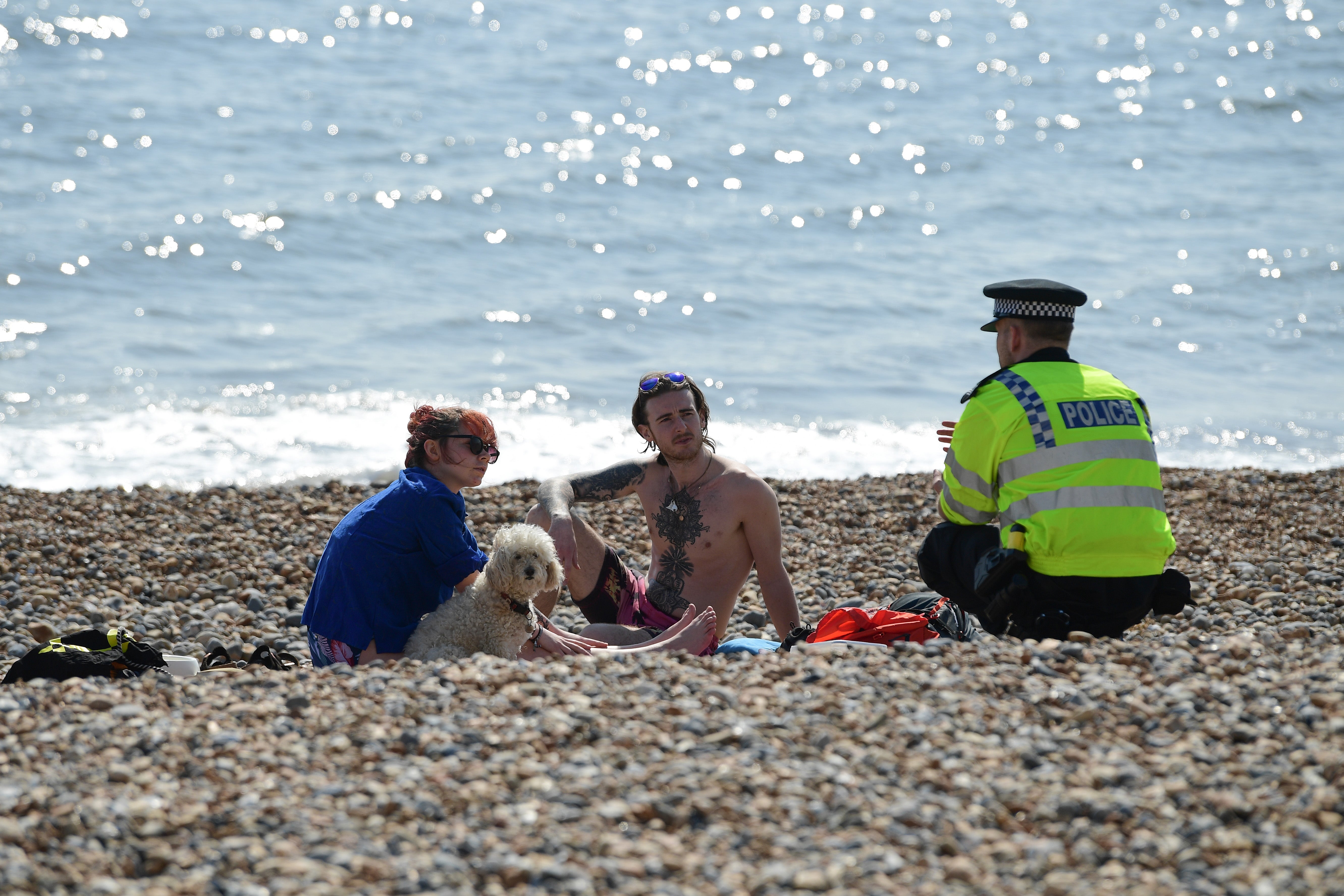 A police officer asks a couple to leave Brighton beach last April