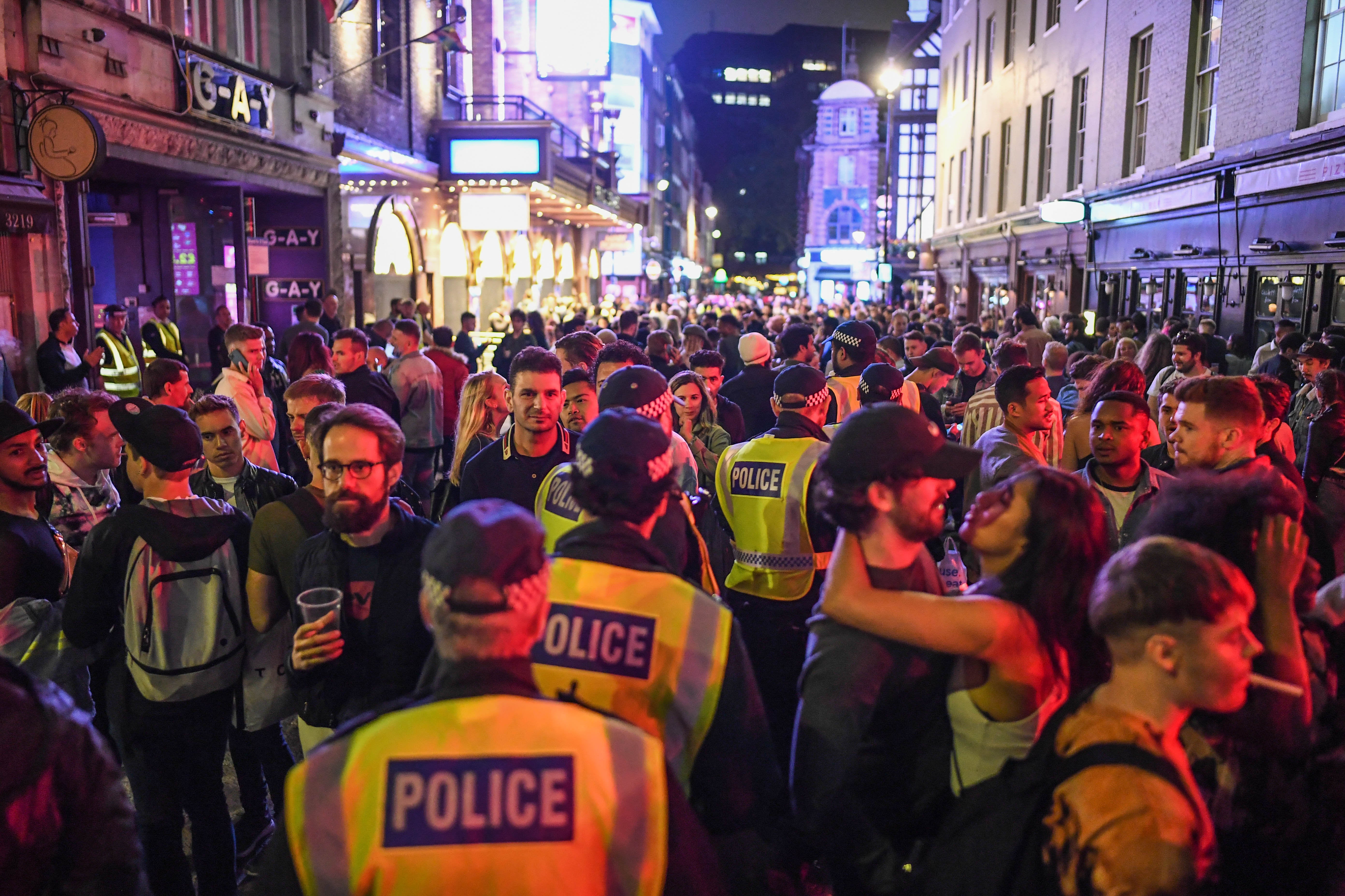 Police officers walking through heavy crowds in Soho on 4 July 2020, the day pubs, clubs and restaurants reopened