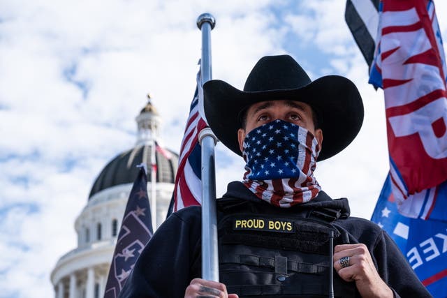 File photo of a member of the Proud Boys watches from the stage as Trump supporters gather at the California State Capitol in Sacramento, California last November