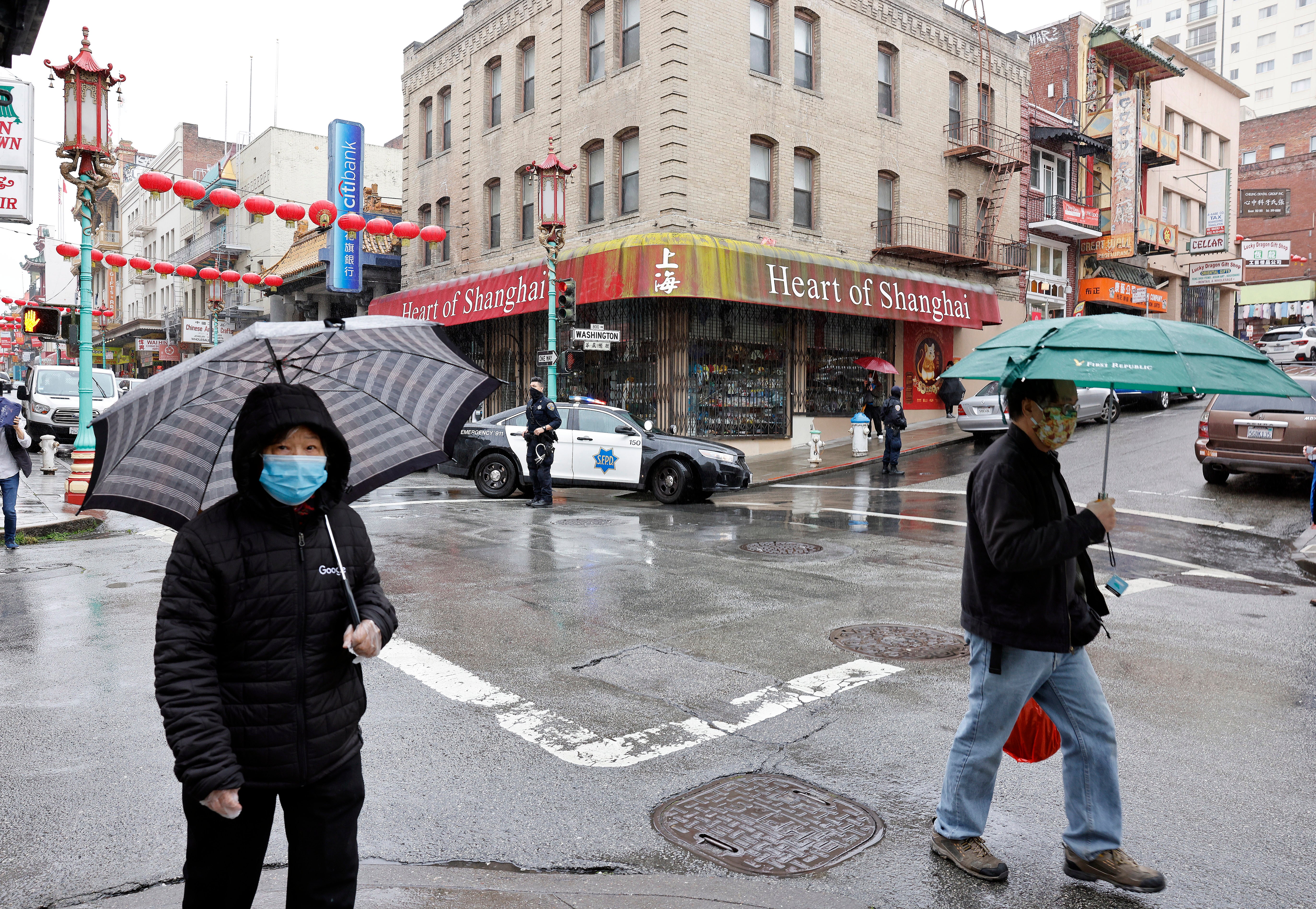 Pedestrians cross the street as San Francisco Police patrol their beat in Chinatown on 18 March