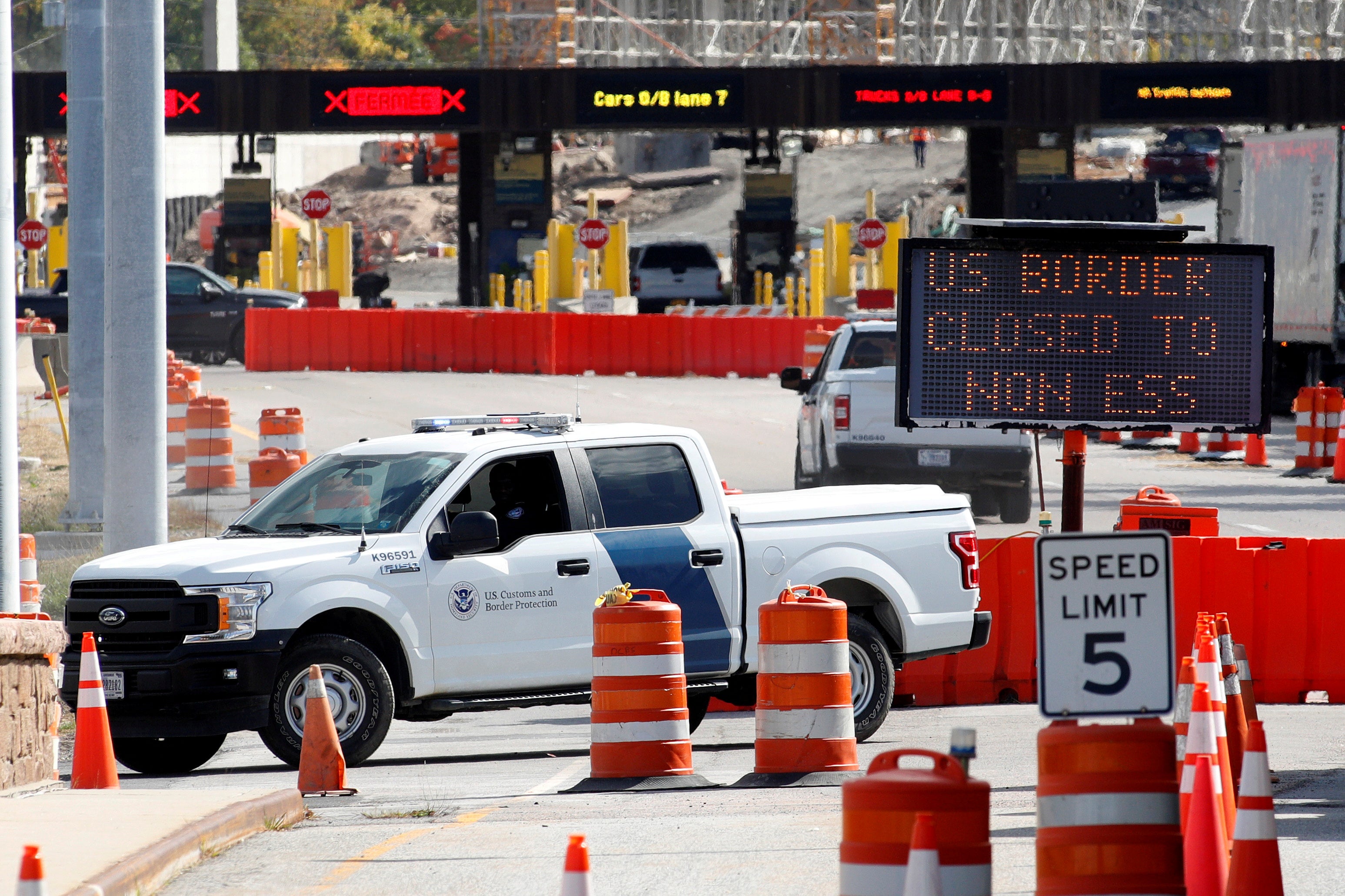 <p>A U.S. Customs and Protection vehicle stands beside a sign reading that the border is closed to non-essential traffic at the Canada-United States border crossing at the Thousand Islands Bridge, to combat the spread of the coronavirus disease</p>