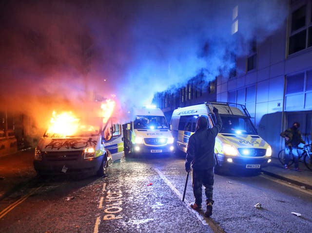 A demonstrator gestures near a burning police van during a protest against a new proposed policing bill in Bristol