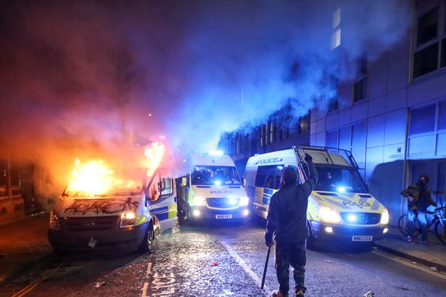 A demonstrator gestures near a burning police van during a protest against a new proposed policing bill in Bristol