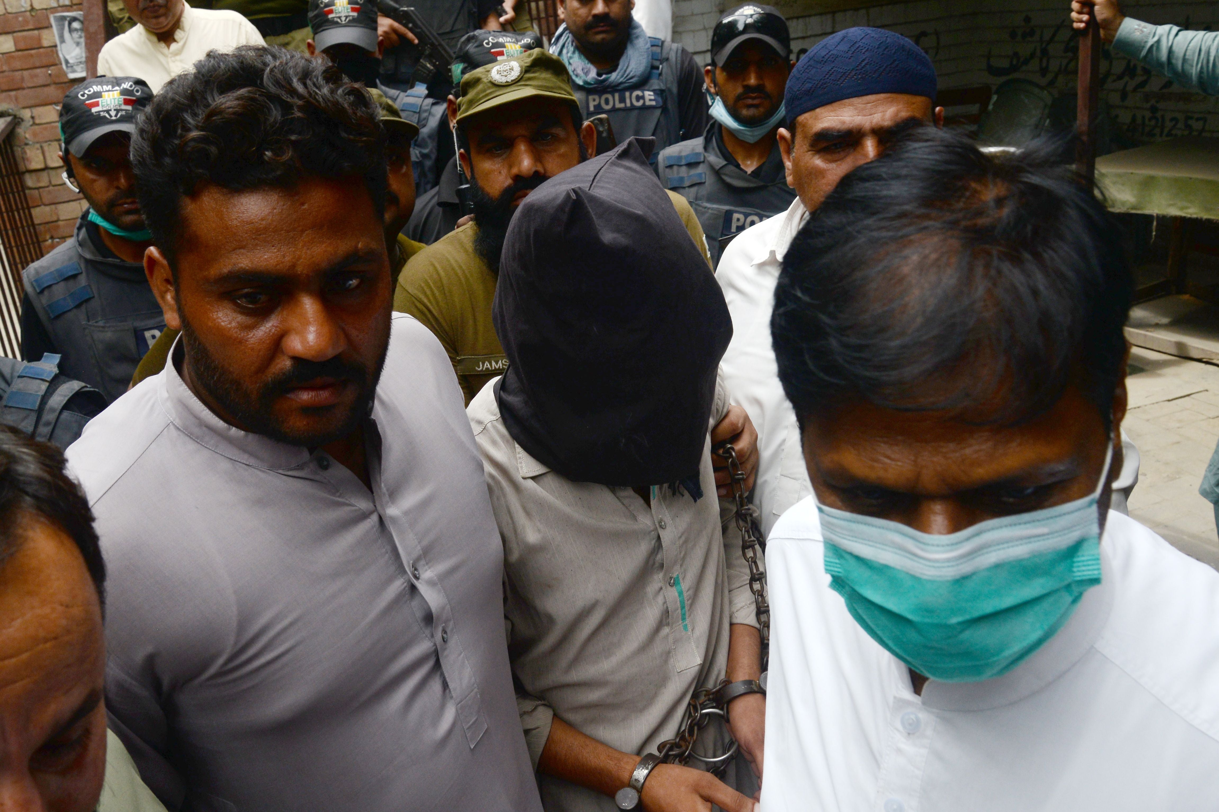 Policemen escort Shafqat Ali (face covered), one of two suspects in the gang-rape case, as they leave from a local court in Lahore on September 15, 2020