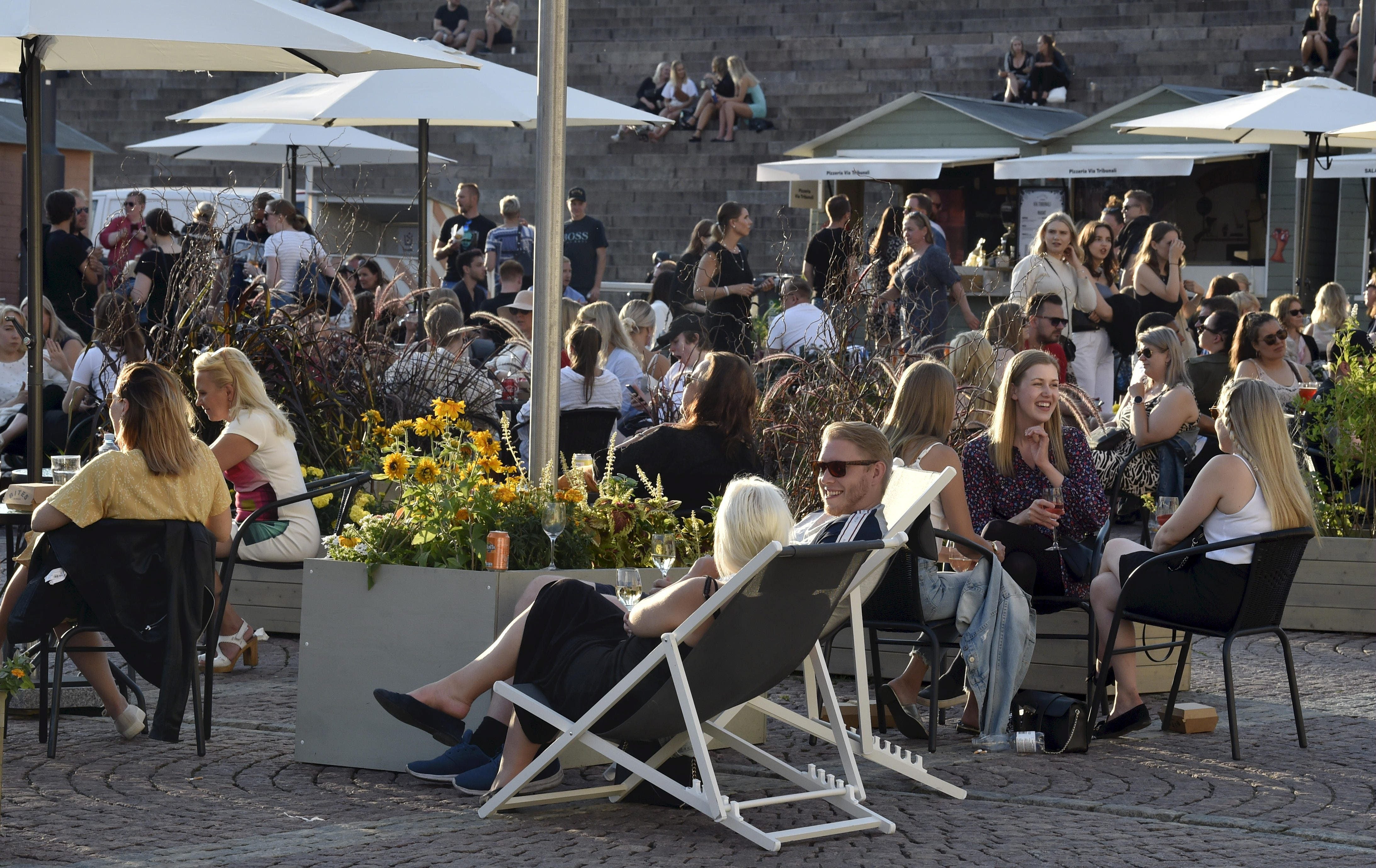 People enjoy meals and drinks on a large open-air food court in the centrally-located Senate Square in Helsinki, Finland, late on 17 July, 2020, the first Friday after a lifting of Covid-19 restrictions.