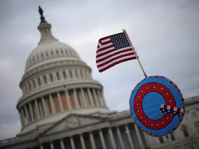 Los partidarios de Donald Trump enarbolan una bandera estadounidense con un símbolo del grupo QAnon mientras se reúnen frente al Capitolio de los Estados Unidos el 6 de enero de 2021 en Washington, DC
